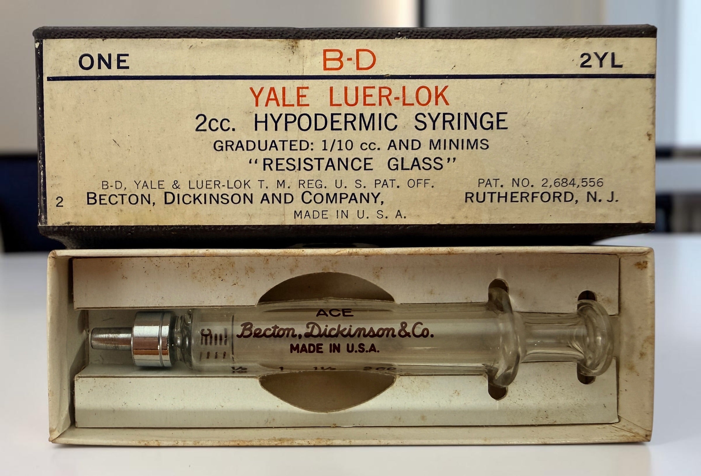 Vintage BD Yale Luer-Lok glass hypodermic syringe with original box. Mid-century medical collectible made in USA for apothecary or scientific display.