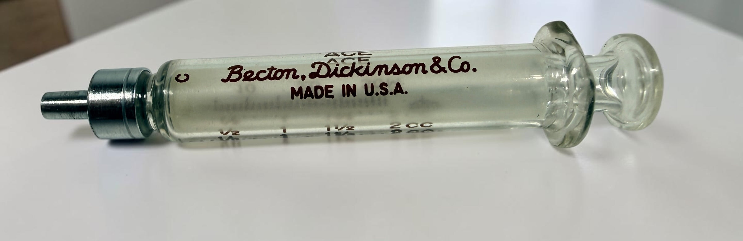 Vintage BD Yale Luer-Lok glass hypodermic syringe with original box. Mid-century medical collectible made in USA for apothecary or scientific display.