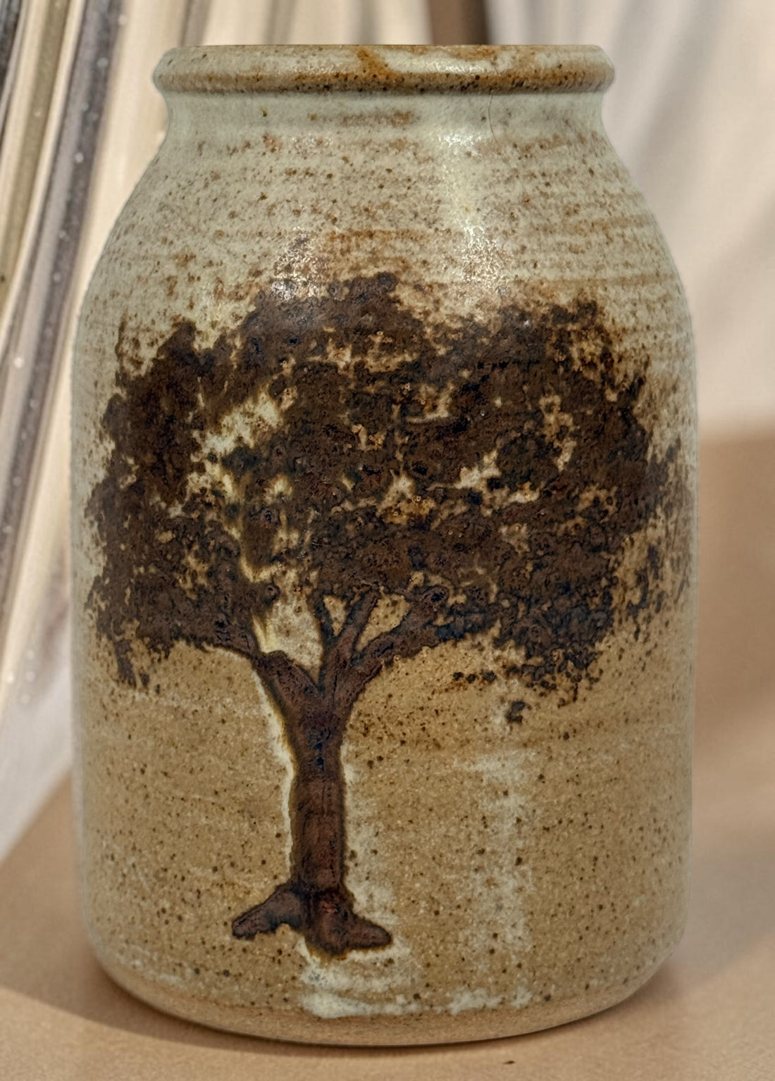 Vintage studio pottery stoneware vase featuring a hand-decorated tree motif and rustic earth-tone glaze. A charming handmade decorative ceramic piece.
