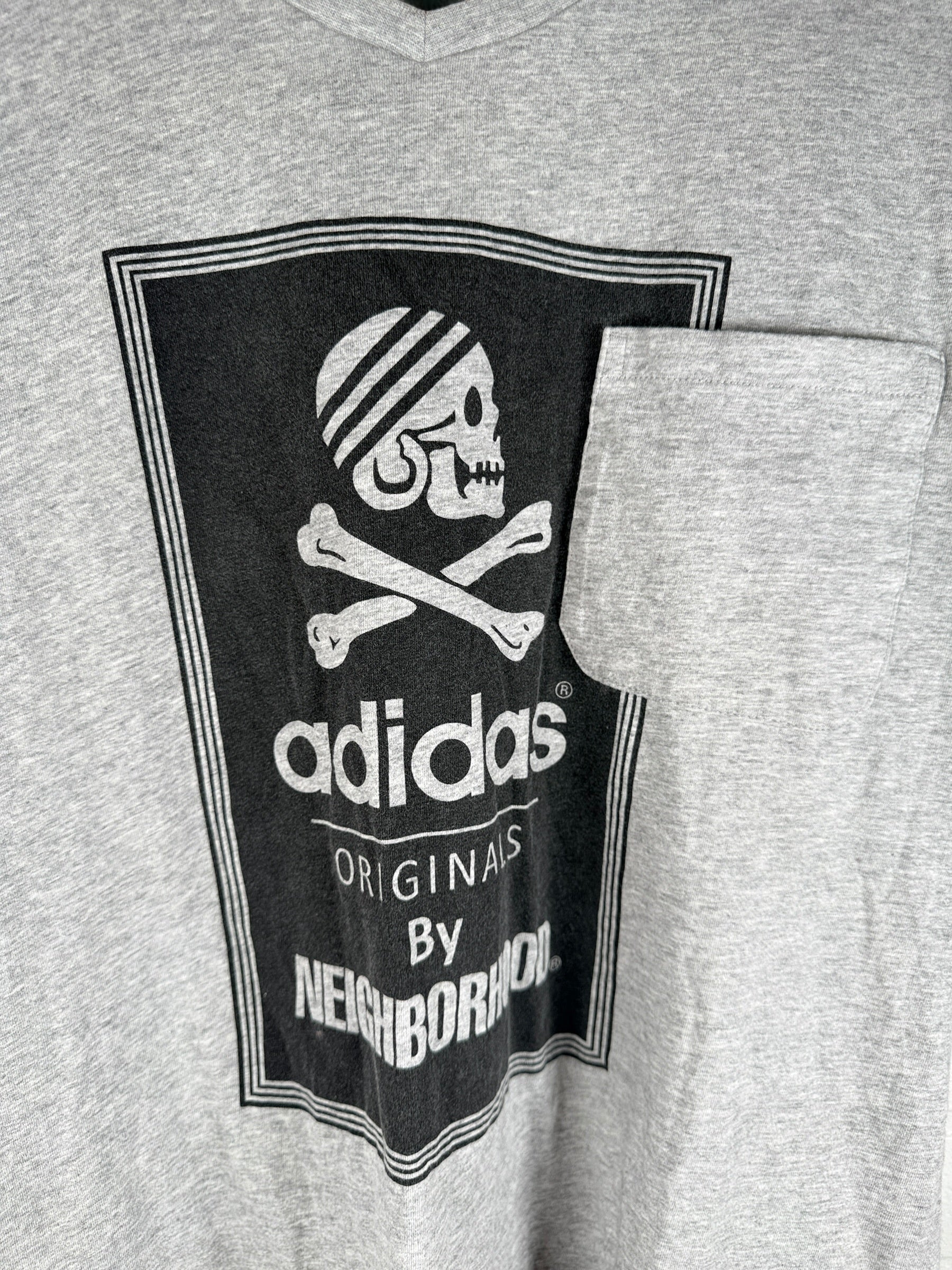 Authentic Adidas Originals x Neighborhood graphic T-shirt in size medium featuring skull artwork, V-neck styling, and collectible Japanese streetwear appeal.