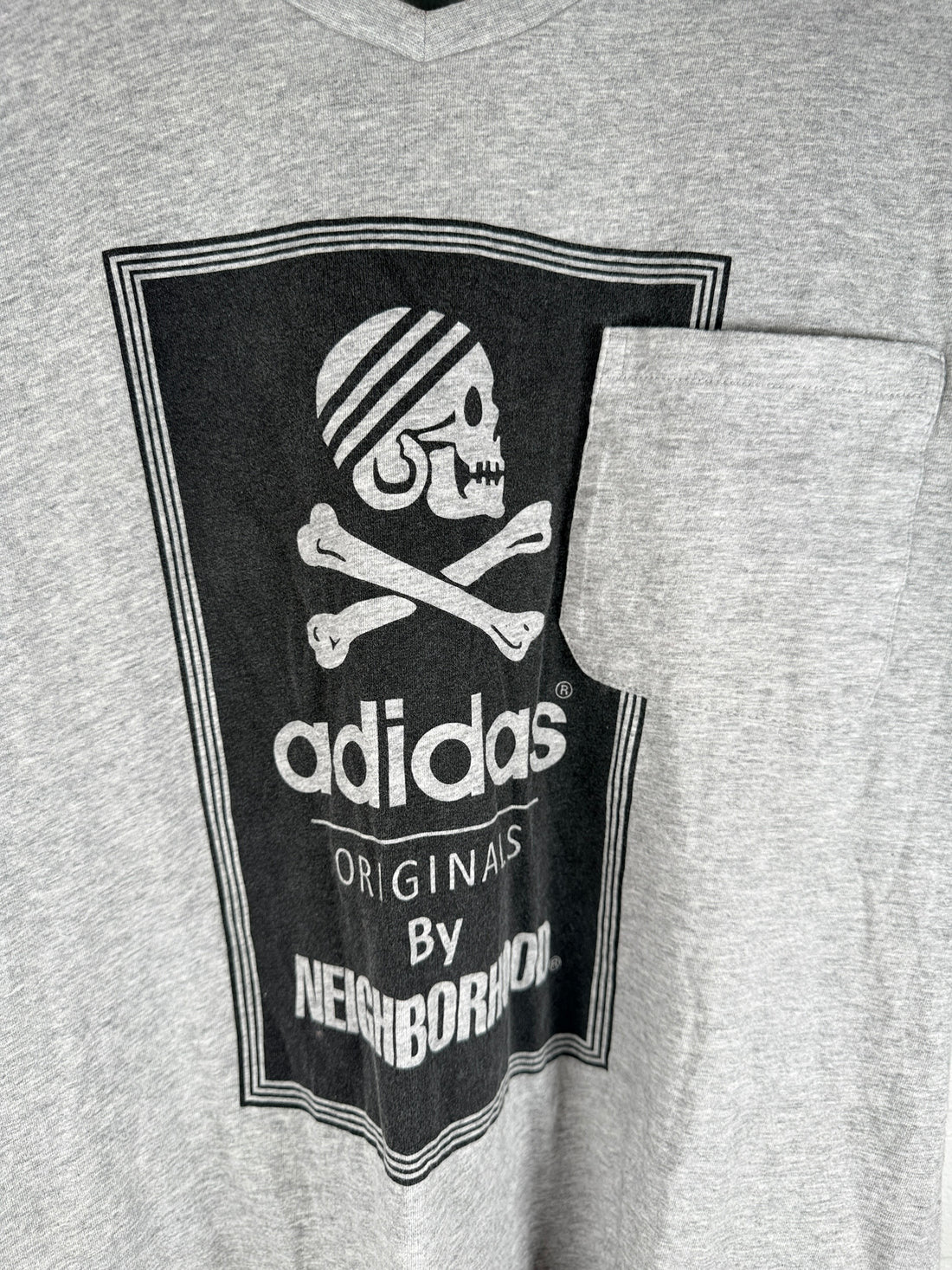Authentic Adidas Originals x Neighborhood graphic T-shirt in size medium featuring skull artwork, V-neck styling, and collectible Japanese streetwear appeal.