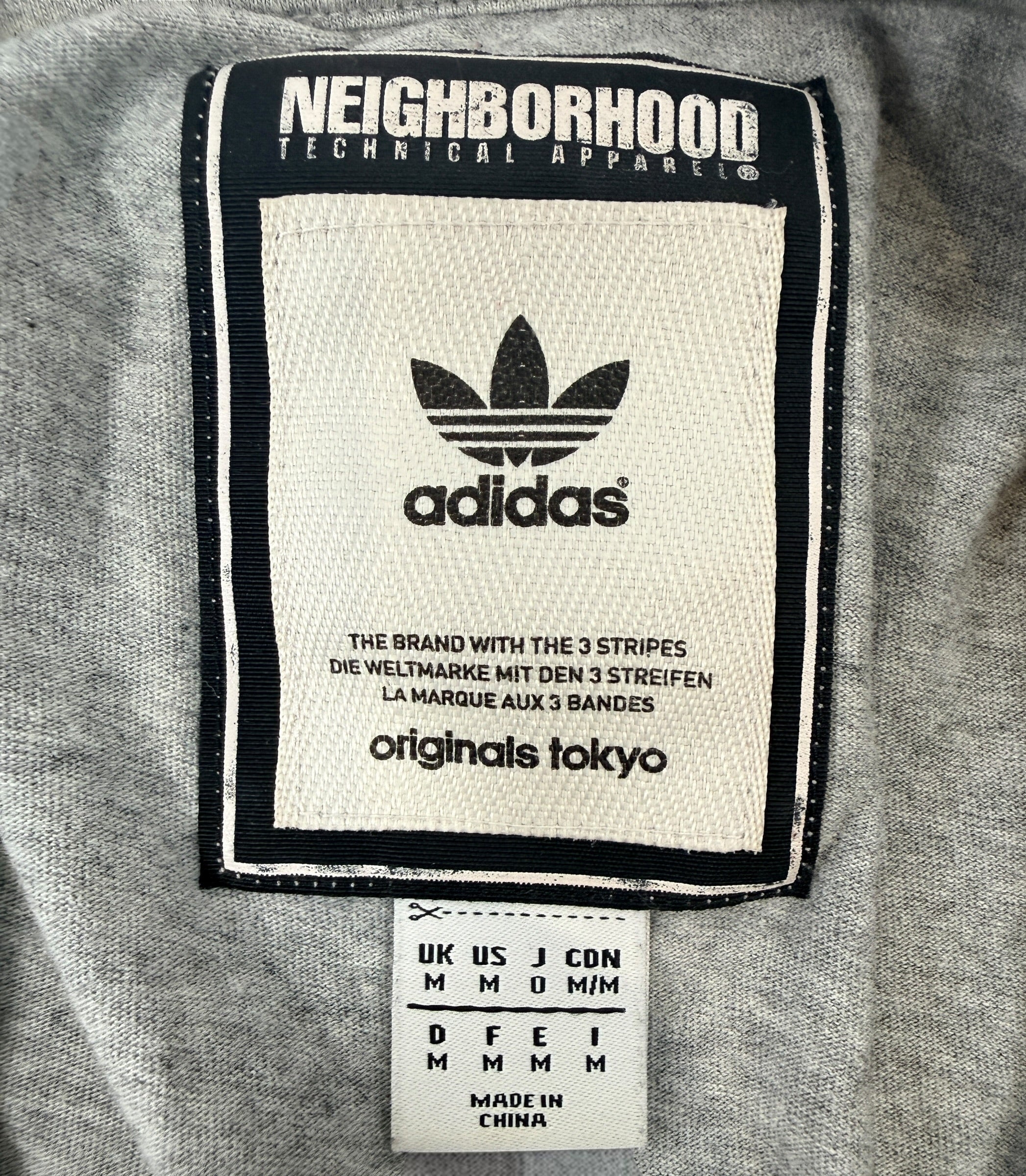 Authentic Adidas Originals x Neighborhood graphic T-shirt in size medium featuring skull artwork, V-neck styling, and collectible Japanese streetwear appeal.