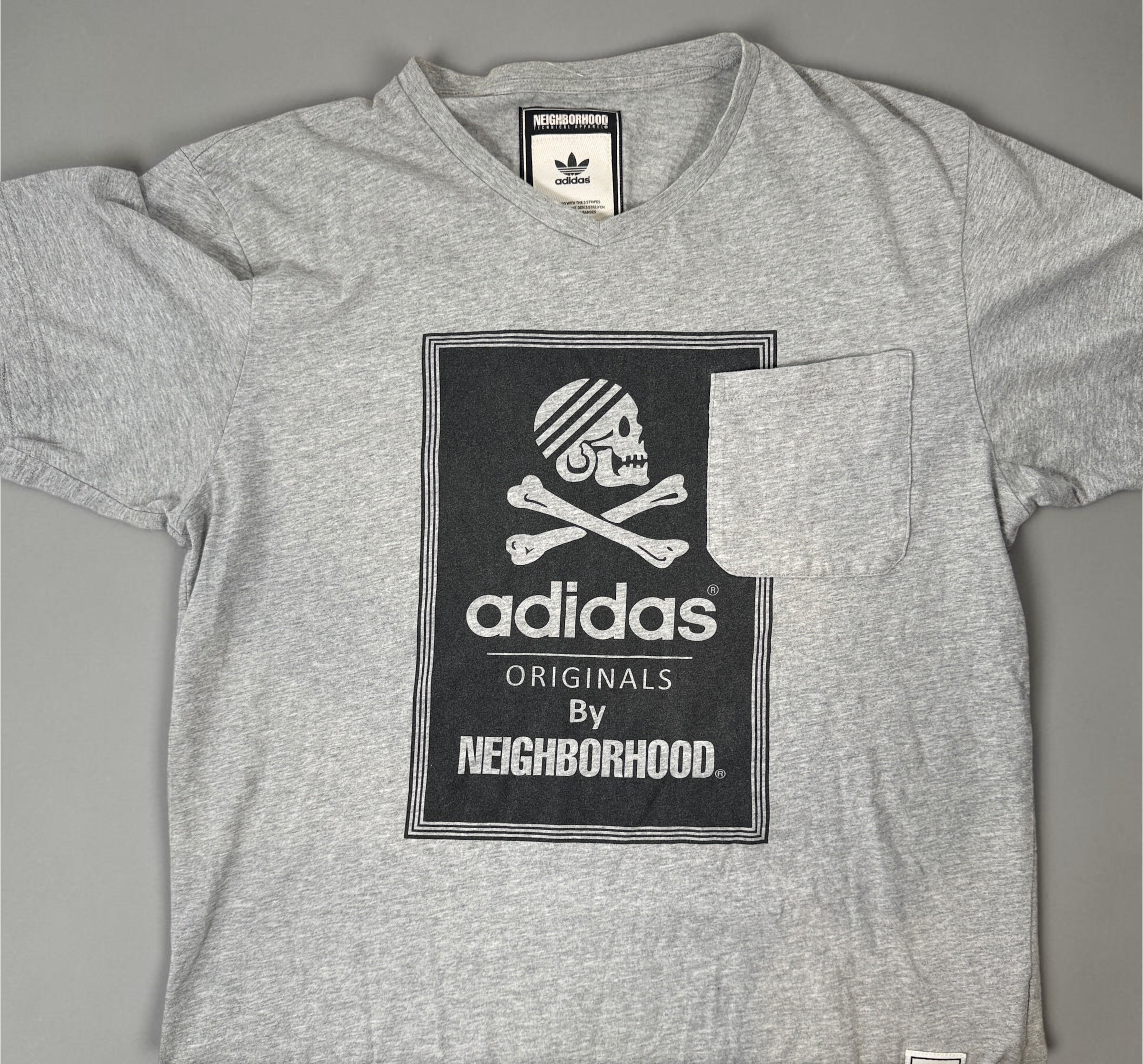 Authentic Adidas Originals x Neighborhood graphic T-shirt in size medium featuring skull artwork, V-neck styling, and collectible Japanese streetwear appeal.