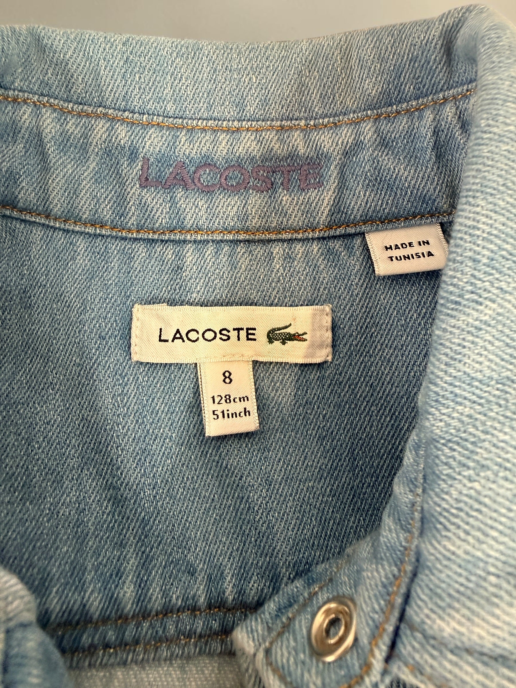 Authentic Lacoste kids denim overshirt in size 8 featuring snap-button closure, chest pockets, and classic crocodile logo. Light wash designer children’s wear.