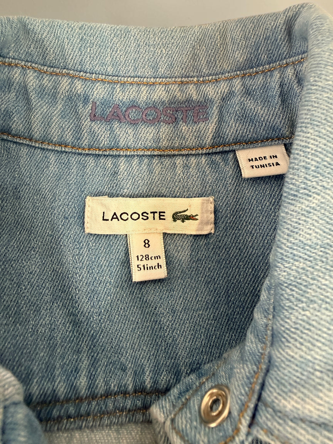 Authentic Lacoste kids denim overshirt in size 8 featuring snap-button closure, chest pockets, and classic crocodile logo. Light wash designer children’s wear.