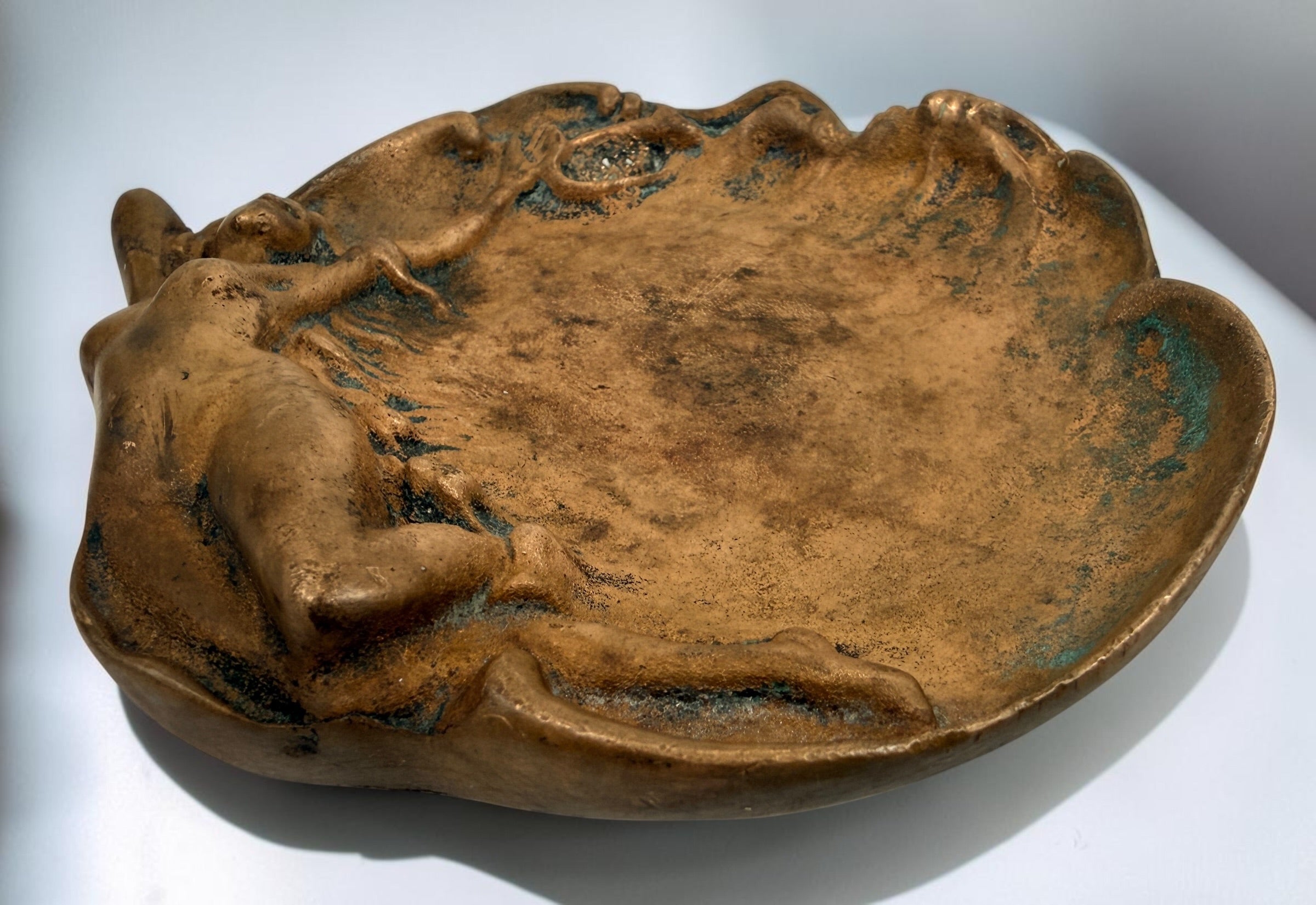Art Nouveau style figural vide-poche tray featuring a reclining nude maiden in cast metal with bronze-tone finish and verdigris patina. Decorative vintage accent.