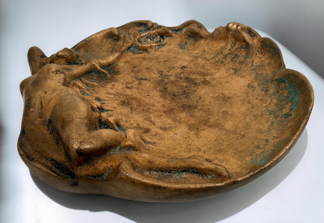 Art Nouveau style figural vide-poche tray featuring a reclining nude maiden in cast metal with bronze-tone finish and verdigris patina. Decorative vintage accent.
