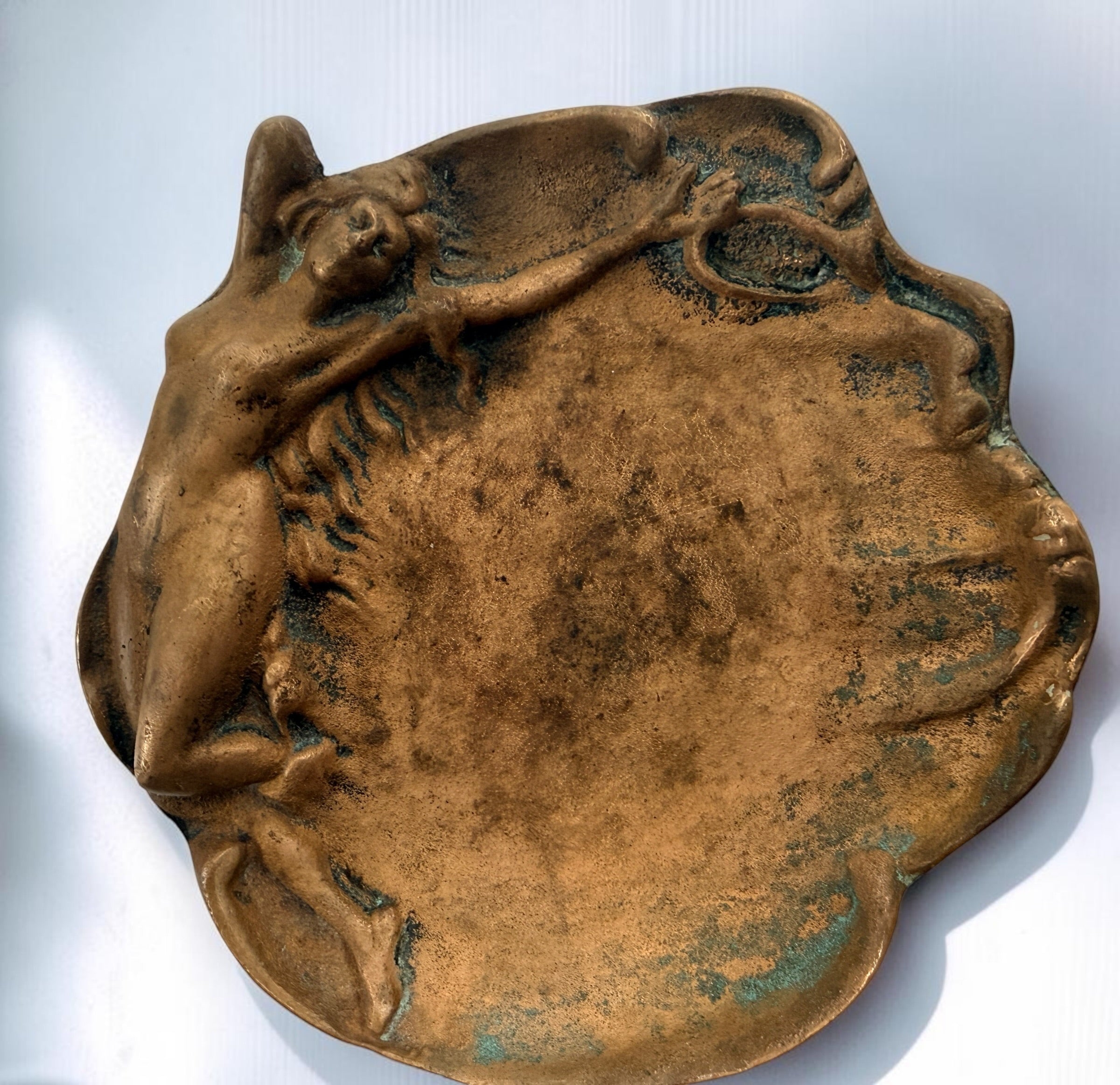 Art Nouveau style figural vide-poche tray featuring a reclining nude maiden in cast metal with bronze-tone finish and verdigris patina. Decorative vintage accent.