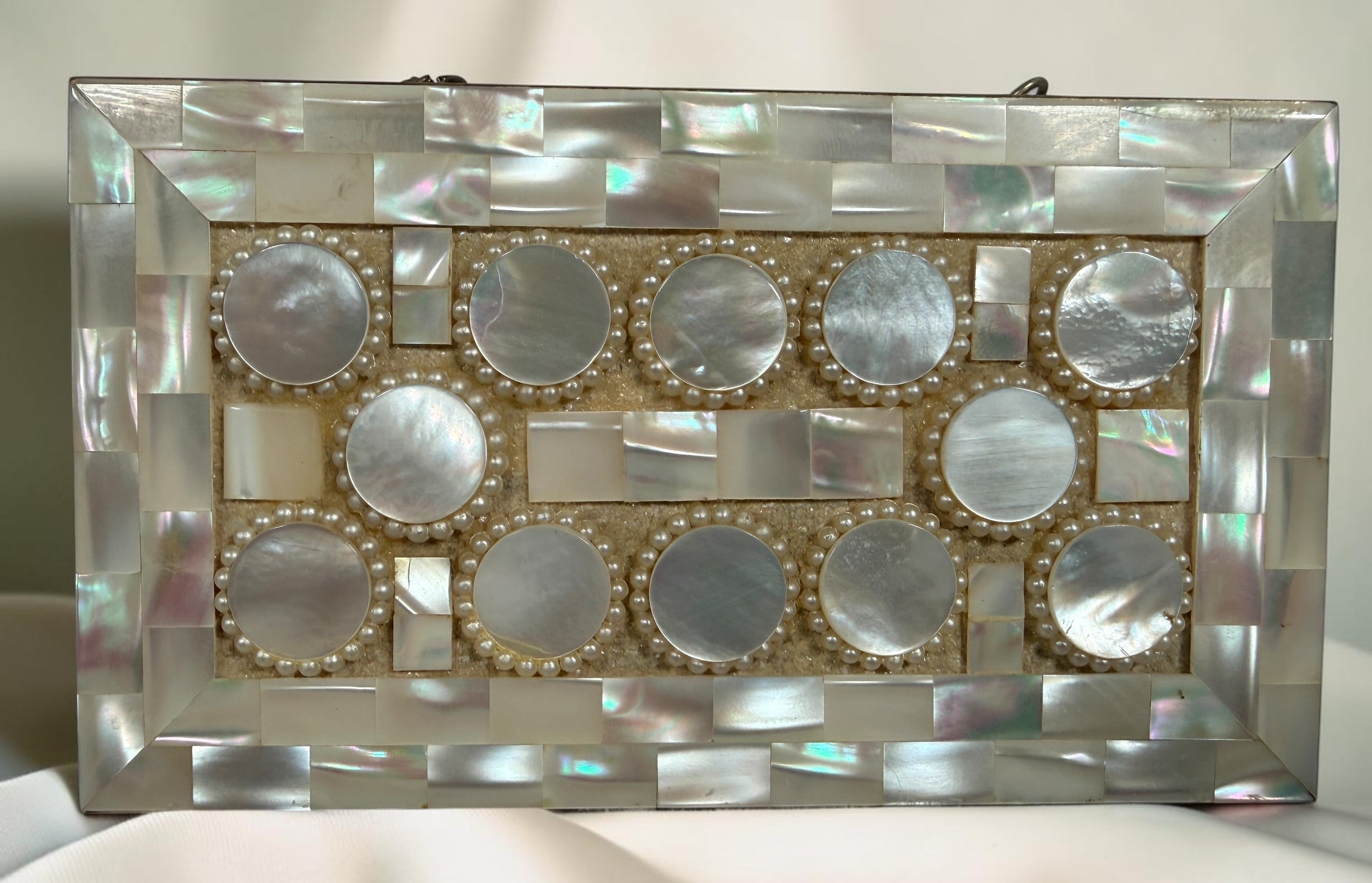 Vintage mother-of-pearl minaudière compact purse with mirror, lipstick holder, and vanity compartments. Elegant mid-century evening accessory.