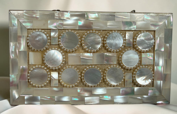 Vintage mother-of-pearl minaudière compact purse with mirror, lipstick holder, and vanity compartments. Elegant mid-century evening accessory.