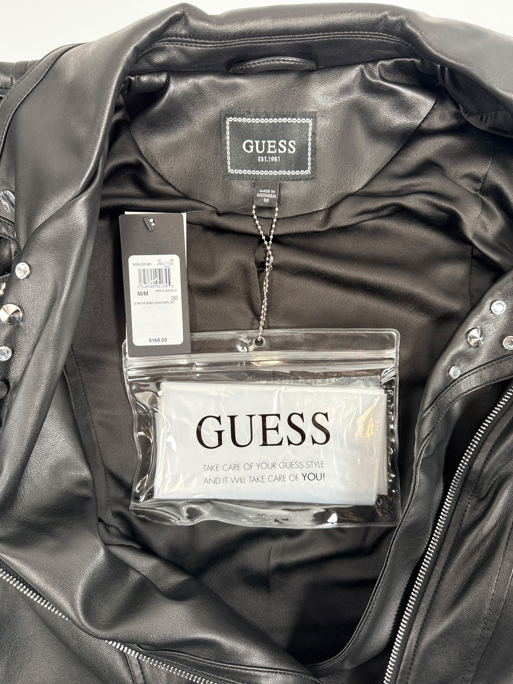 GUESS studded faux leather moto jacket in black, size medium. New with tags featuring rhinestone accents, asymmetrical zip closure and cropped biker styling.