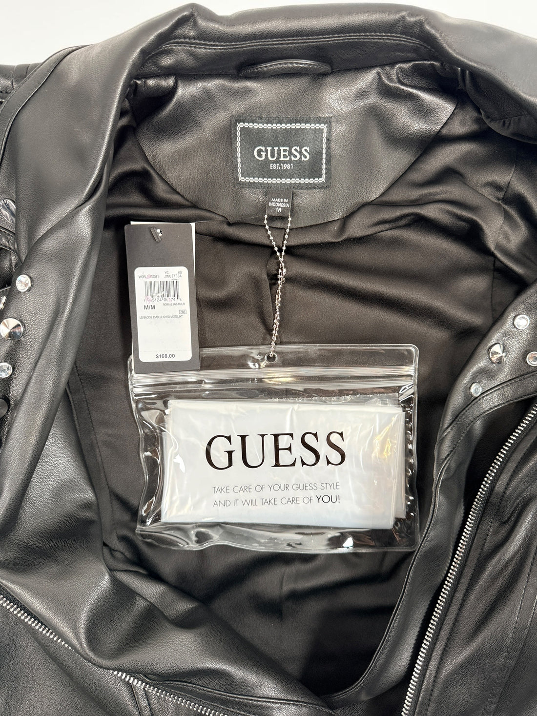 GUESS studded faux leather moto jacket in black, size medium. New with tags featuring rhinestone accents, asymmetrical zip closure and cropped biker styling.