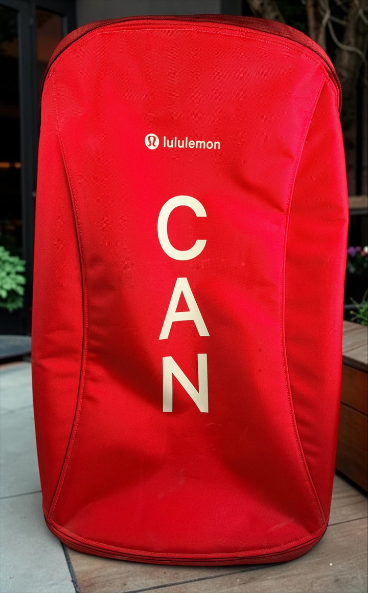 Official Lululemon Team Canada rolling suitcase in vibrant Olympic red. Large wheeled travel luggage with spacious interior, compression straps, and rare Canadian Olympic branding