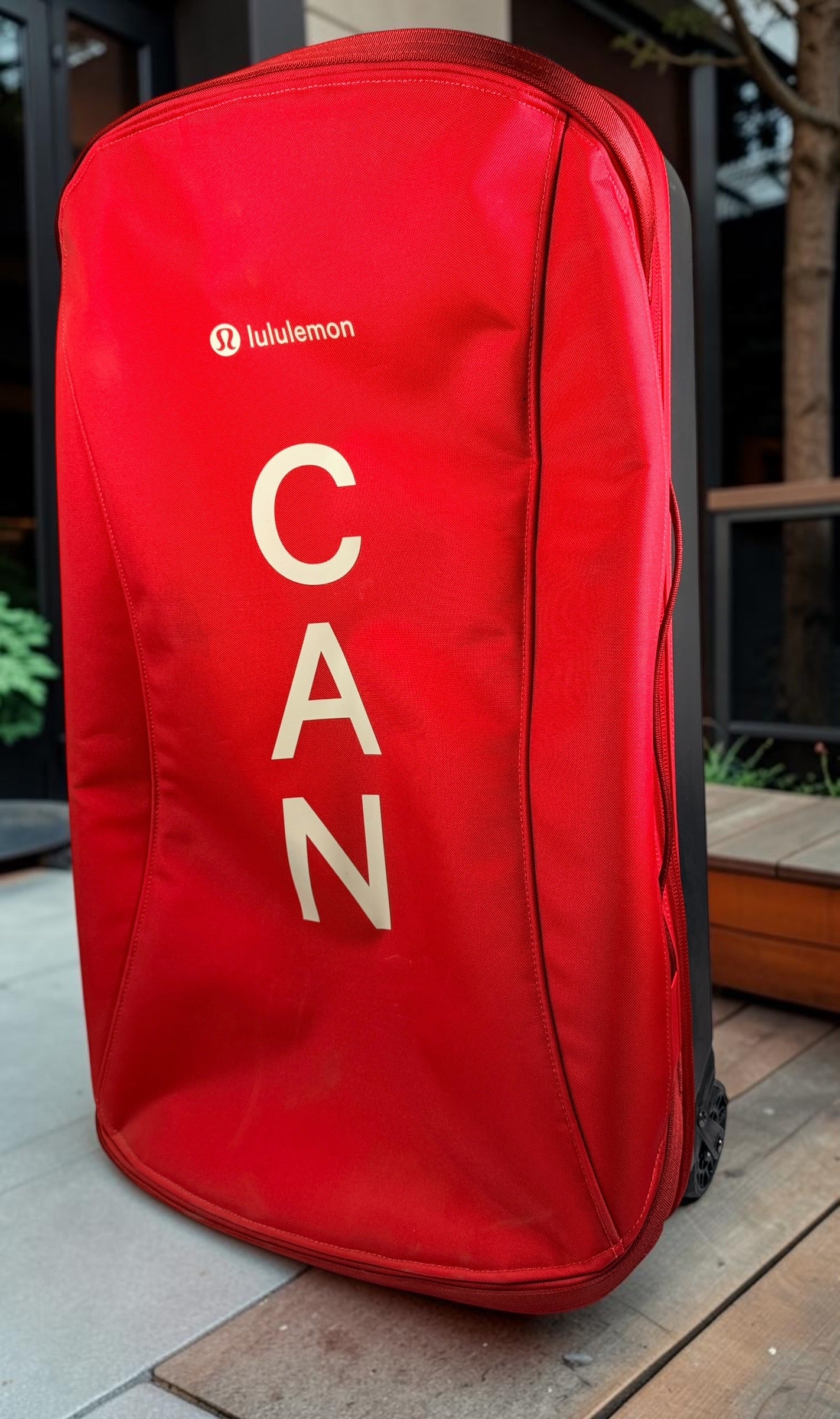 Official Lululemon Team Canada rolling suitcase in vibrant Olympic red. Large wheeled travel luggage with spacious interior, compression straps, and rare Canadian Olympic branding