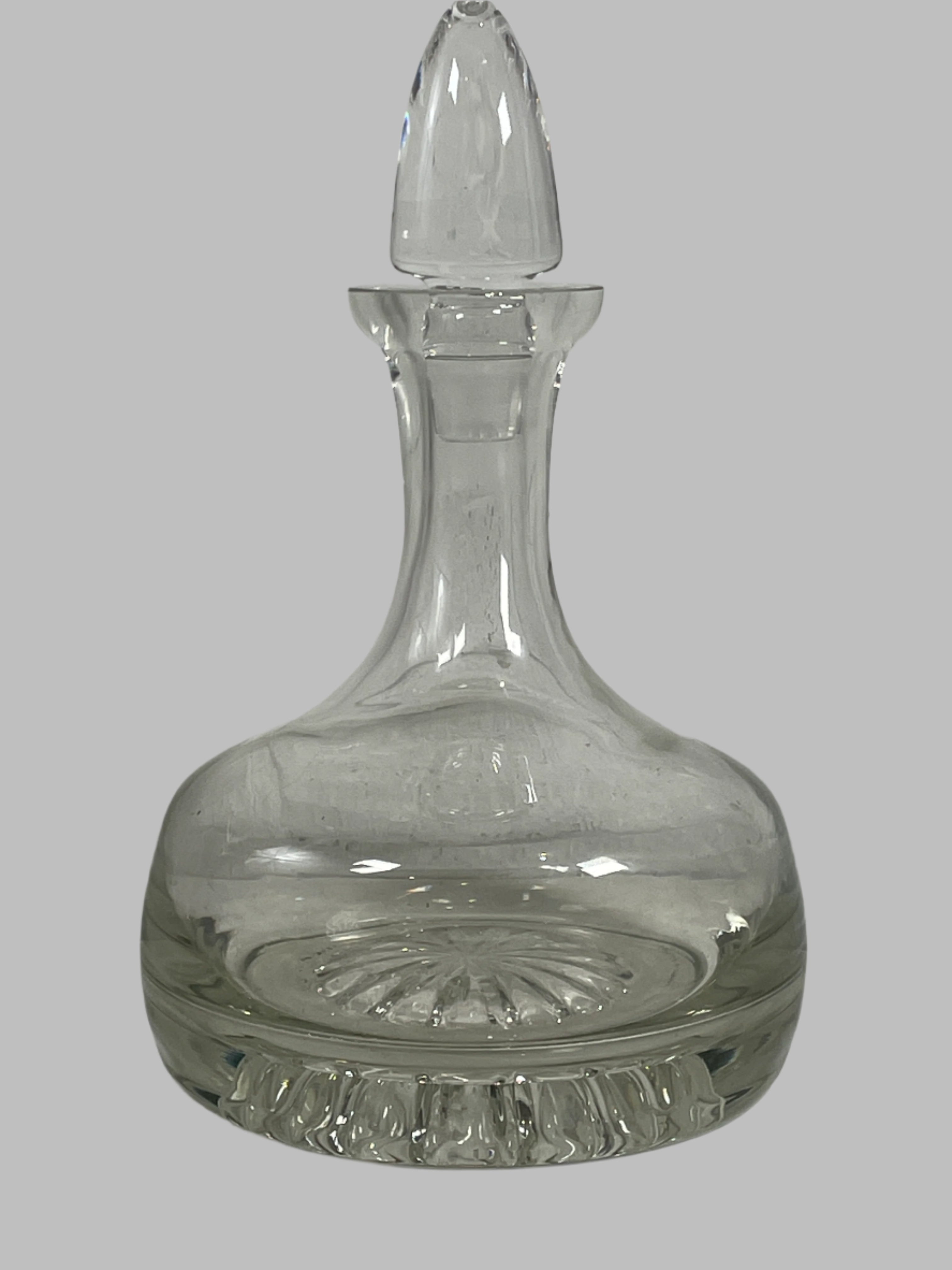 Clear glass decanter with intricate design on a white textured background