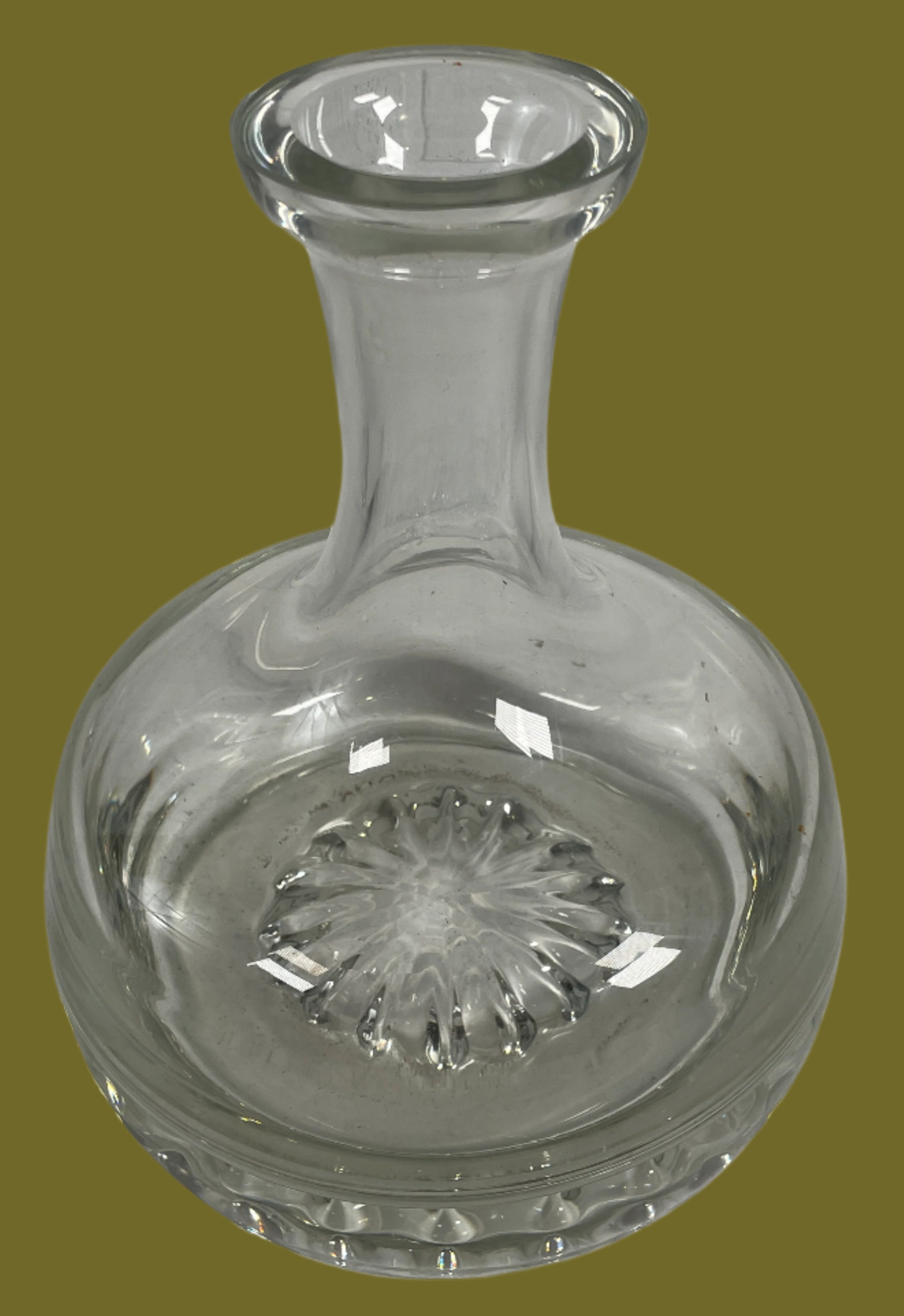 Clear glass decanter with a textured stopper on a light gray background