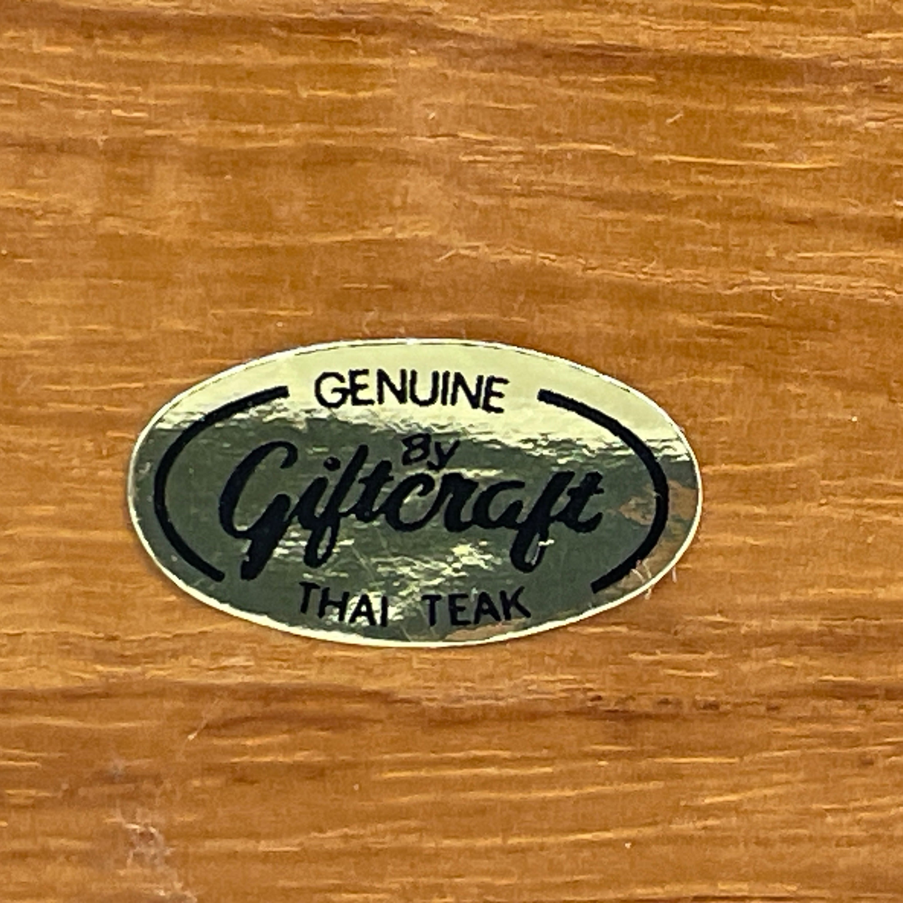 Genuine Giftcraft Thai Teak logo on a wooden surface