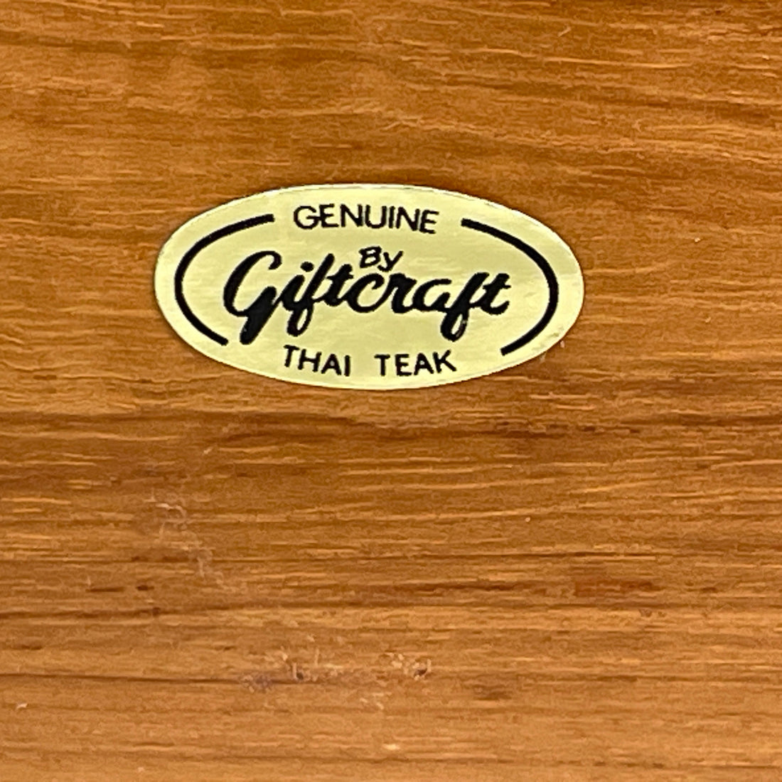 Genuine by Giftcraft Thai Teak logo on a wooden surface
