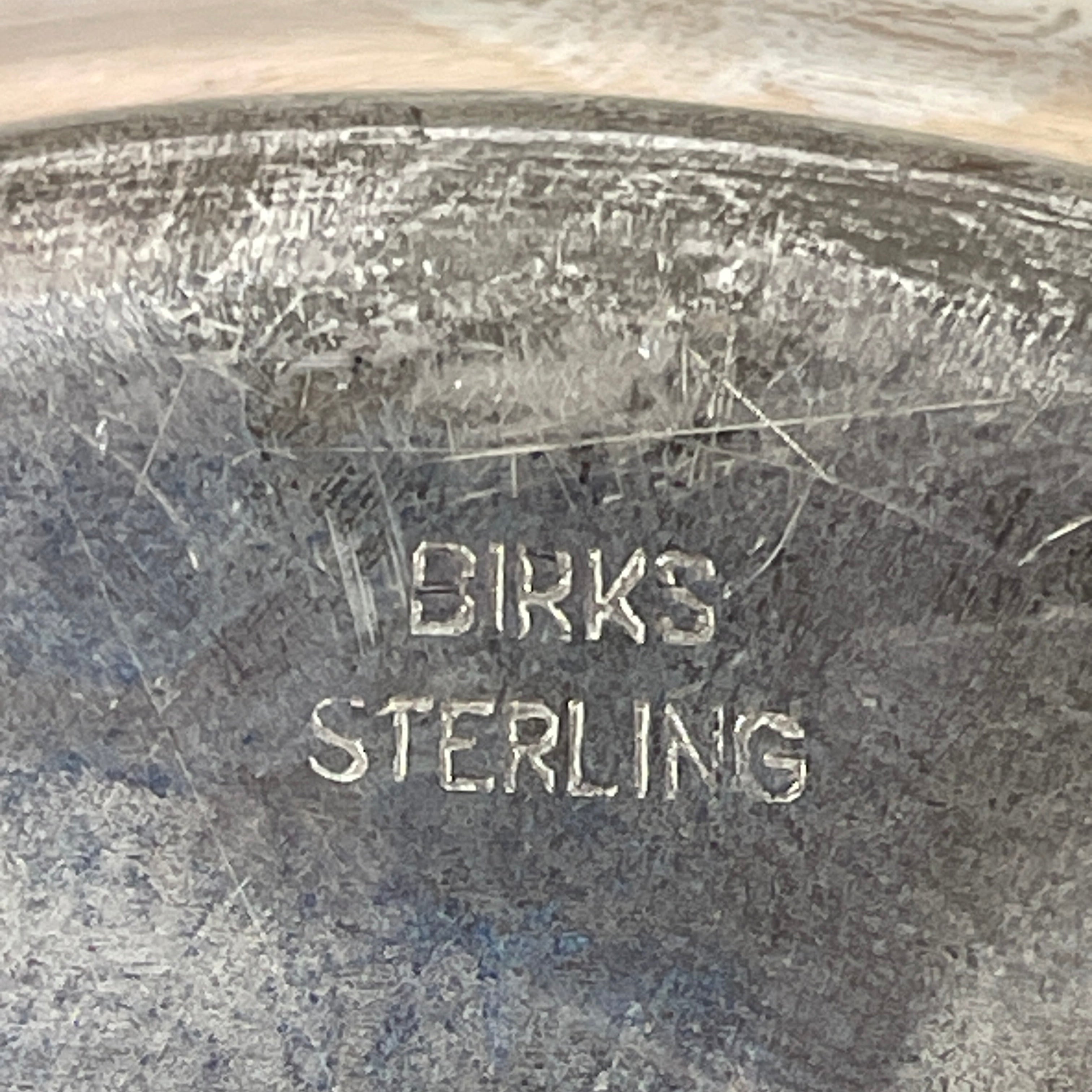 Close-up of a silver object with 'Birks Sterling' engraving.