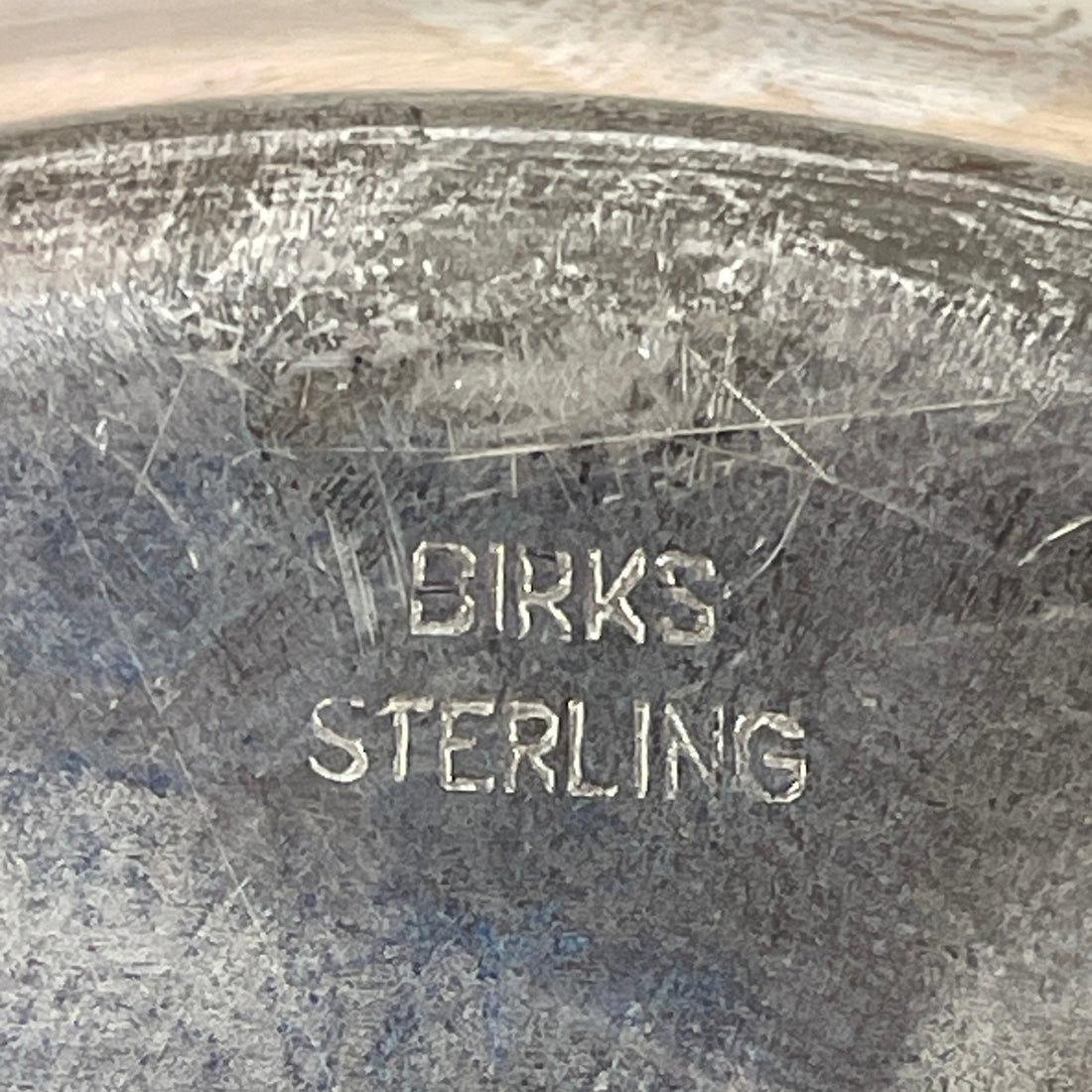 Close-up of a silver object with 'Birks Sterling' engraving.