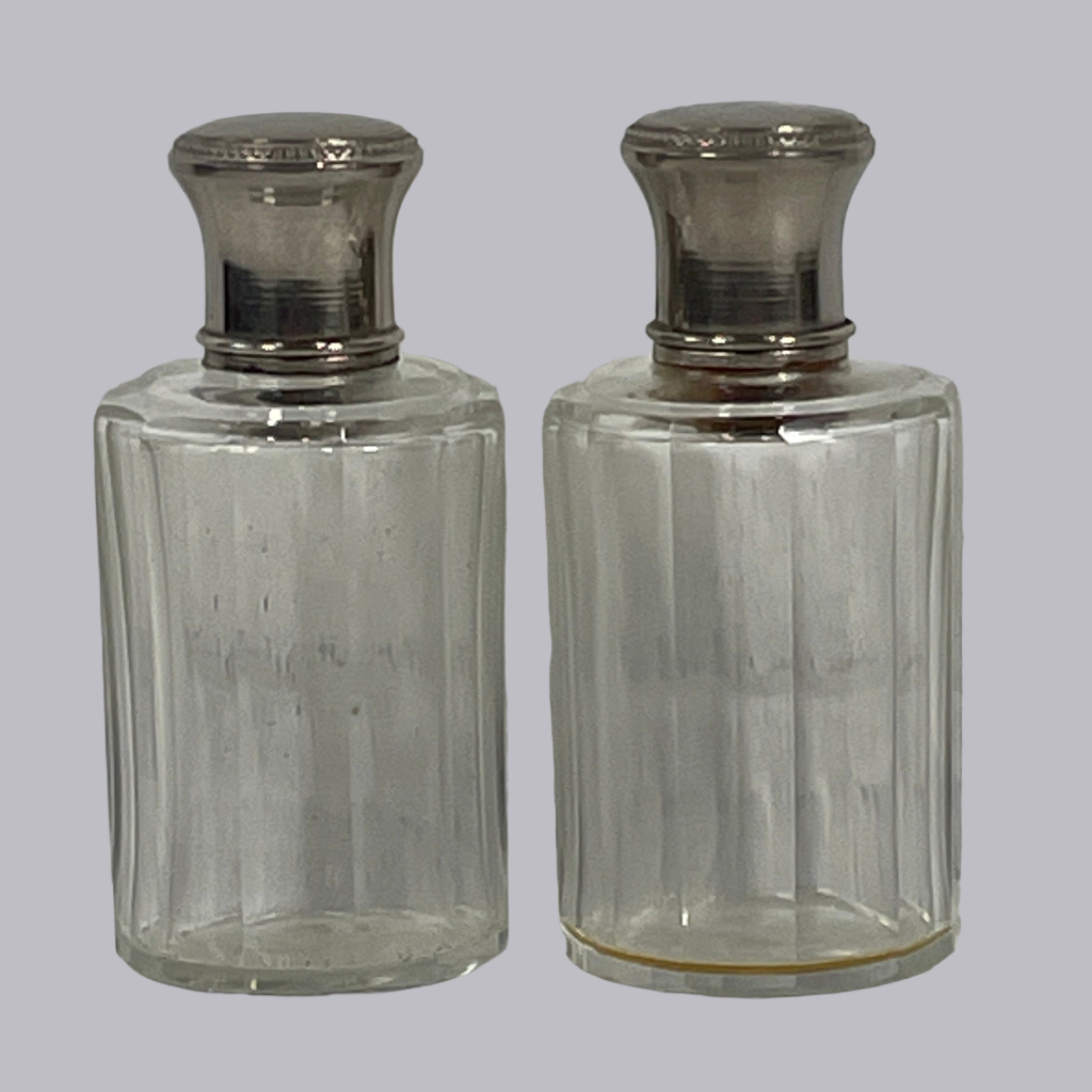 Two clear glass bottles with silver caps on a light gray surface.