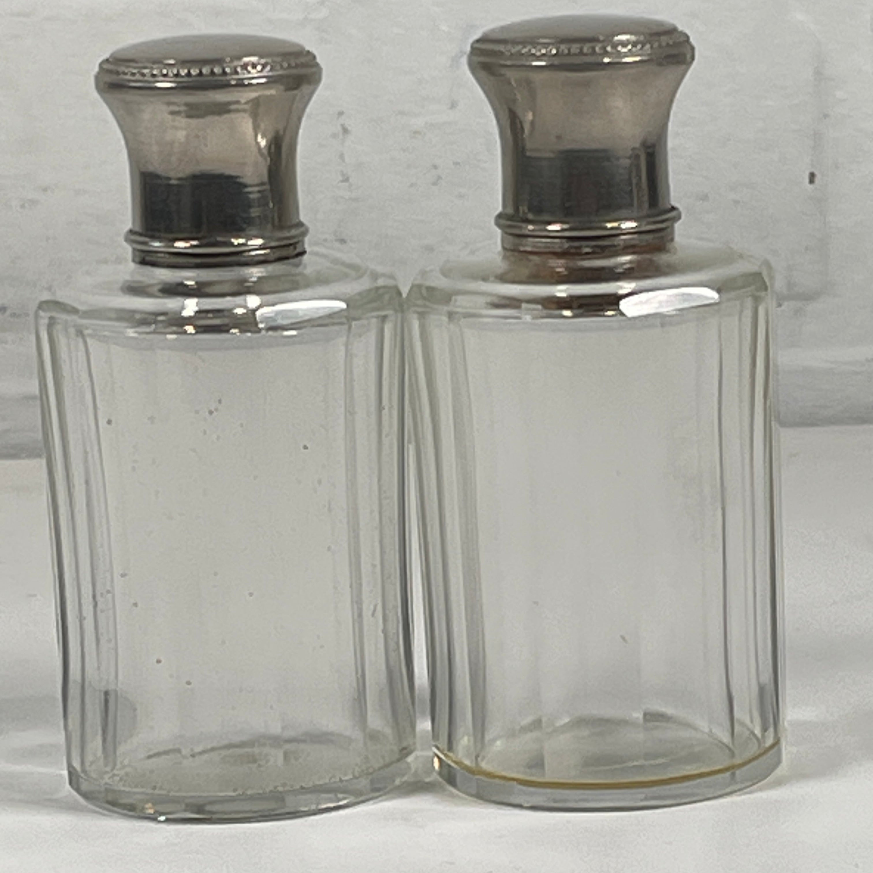 Clear glass decanter with silver stoppers on a white background
