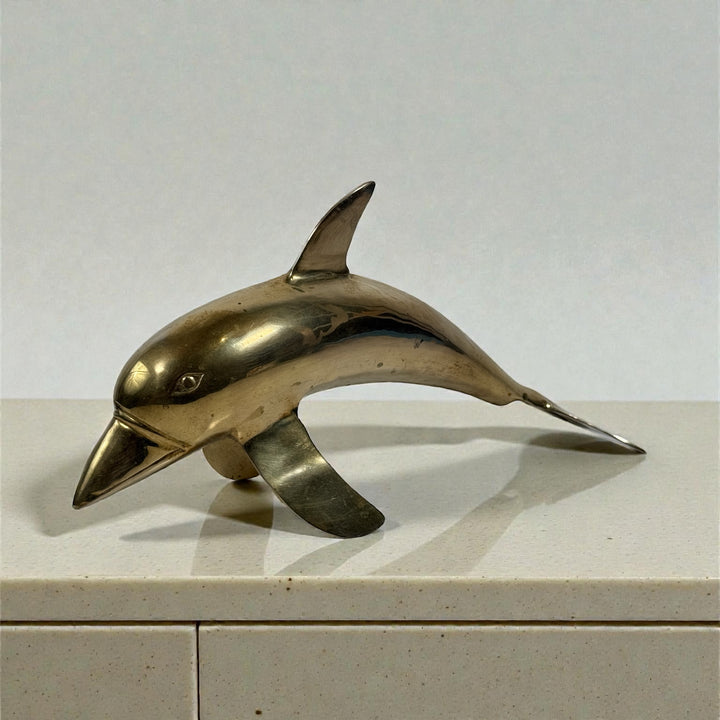 Vintage solid brass dolphin sculpture, mid-century coastal decor accent. Heavy cast brass with original patina. Classic Hollywood Regency style.