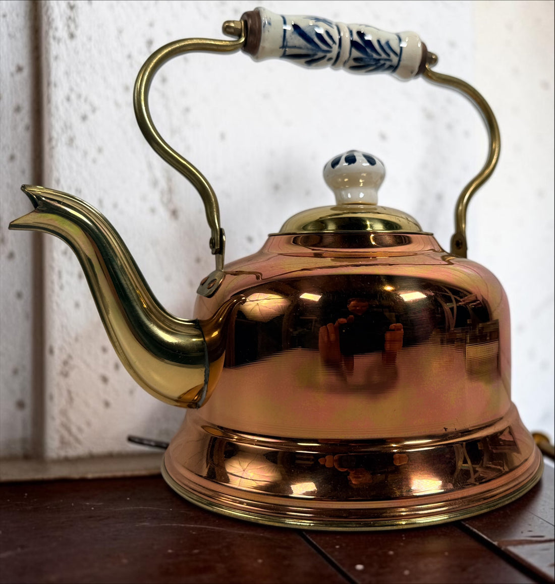Vintage copper and brass tea kettle with blue-and-white porcelain handle and lid knob. Decorative Delft-style vintage kitchen collectible.