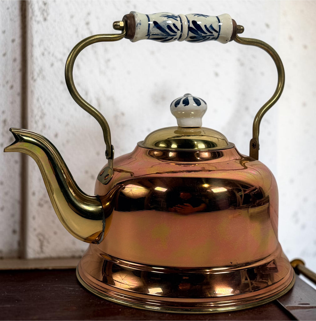 Vintage copper and brass tea kettle with blue-and-white porcelain handle and lid knob. Decorative Delft-style vintage kitchen collectible.