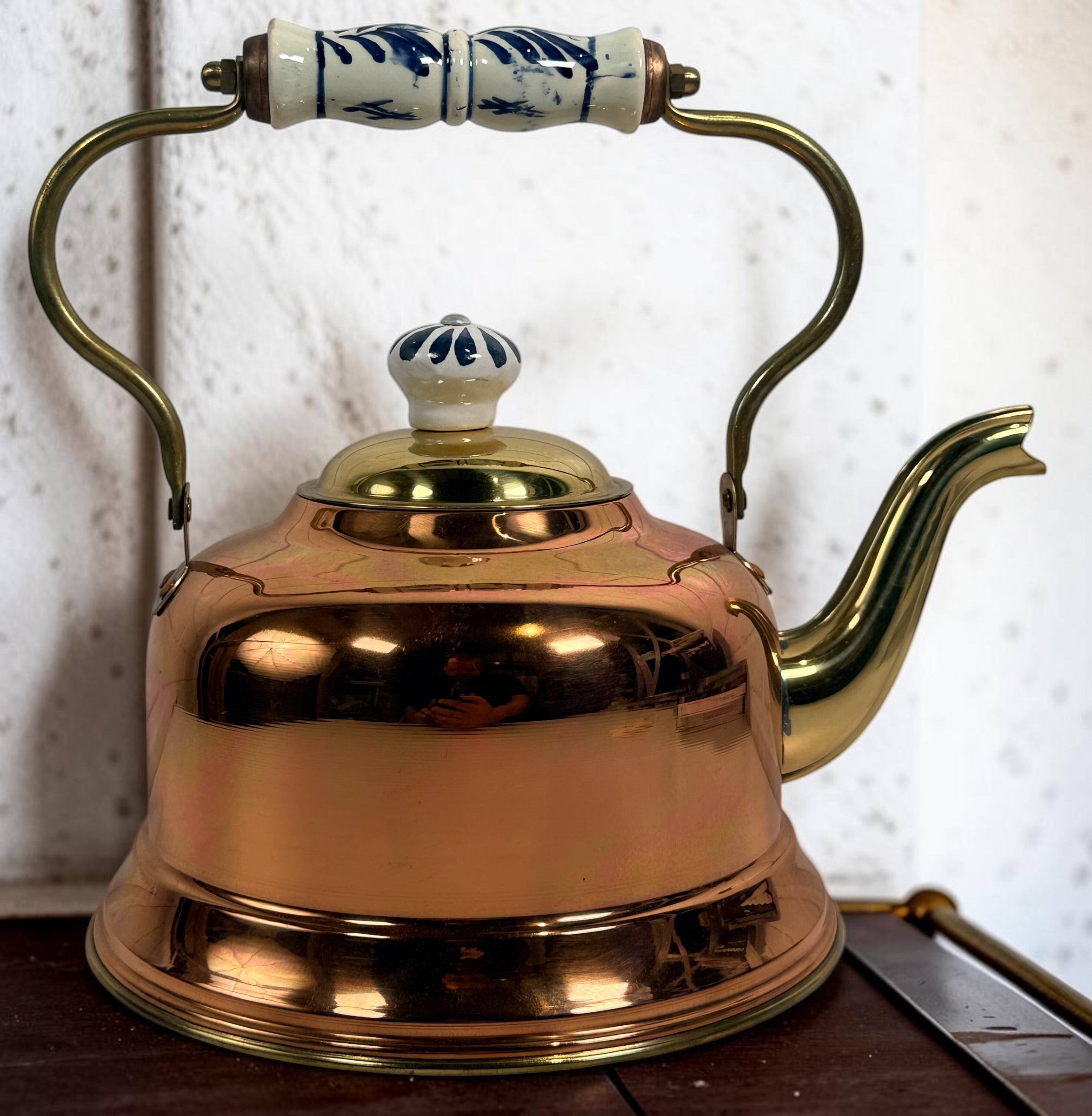 Vintage copper and brass tea kettle with blue-and-white porcelain handle and lid knob. Decorative Delft-style vintage kitchen collectible.