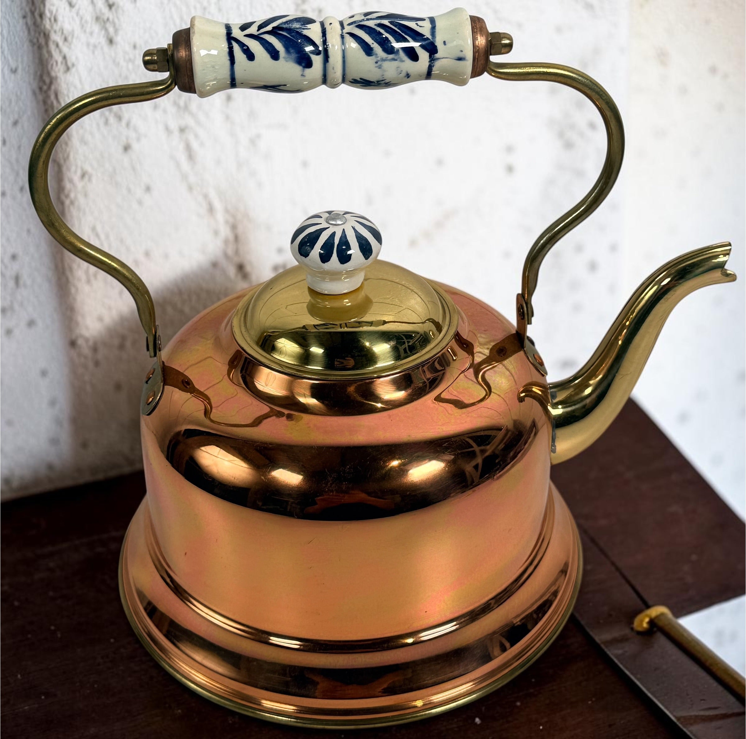 Vintage copper and brass tea kettle with blue-and-white porcelain handle and lid knob. Decorative Delft-style vintage kitchen collectible.