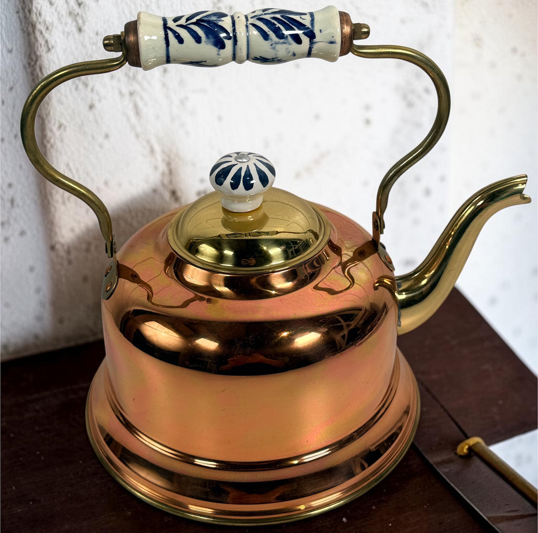 Vintage copper and brass tea kettle with blue-and-white porcelain handle and lid knob. Decorative Delft-style vintage kitchen collectible.