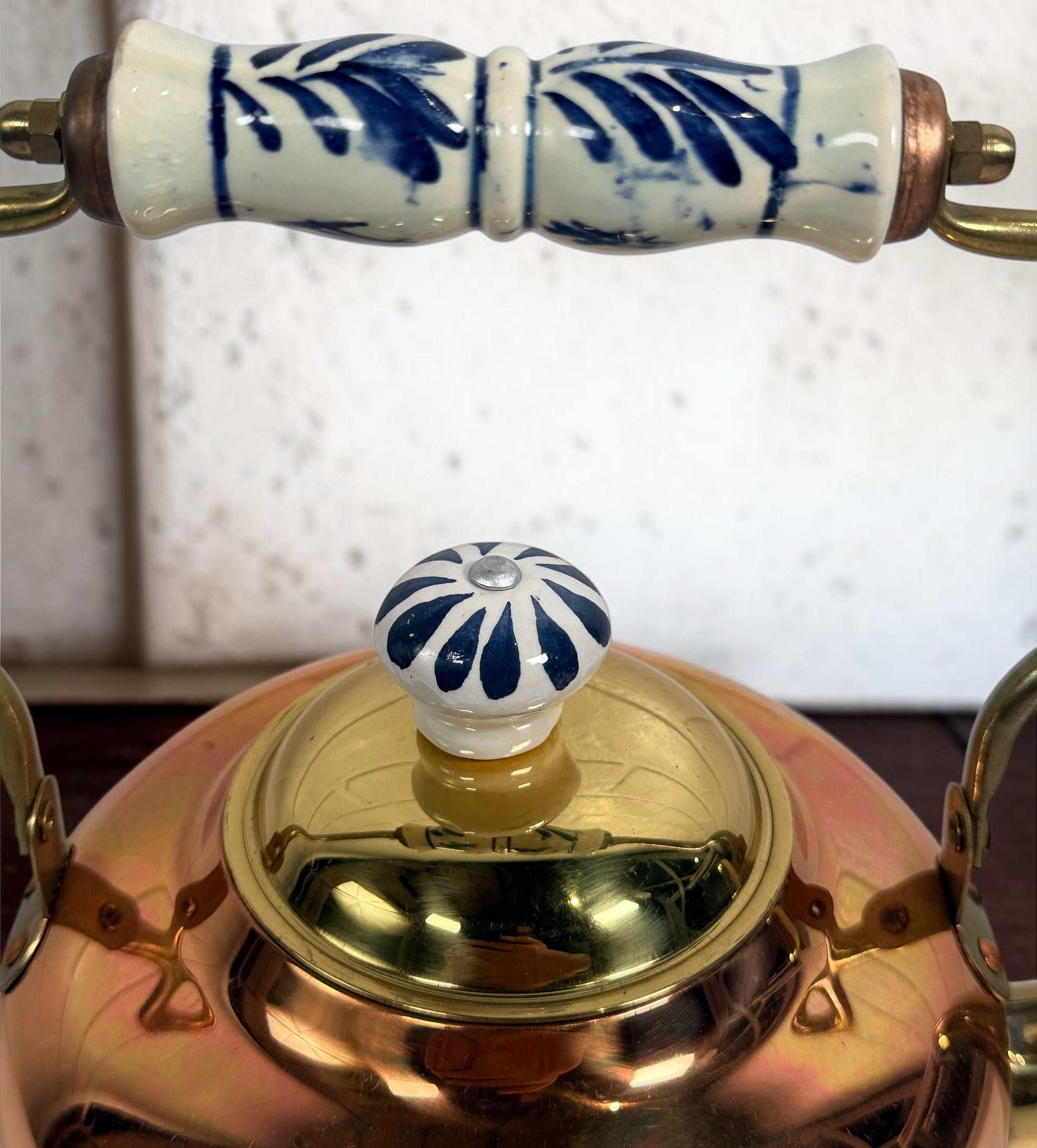 Vintage copper and brass tea kettle with blue-and-white porcelain handle and lid knob. Decorative Delft-style vintage kitchen collectible.