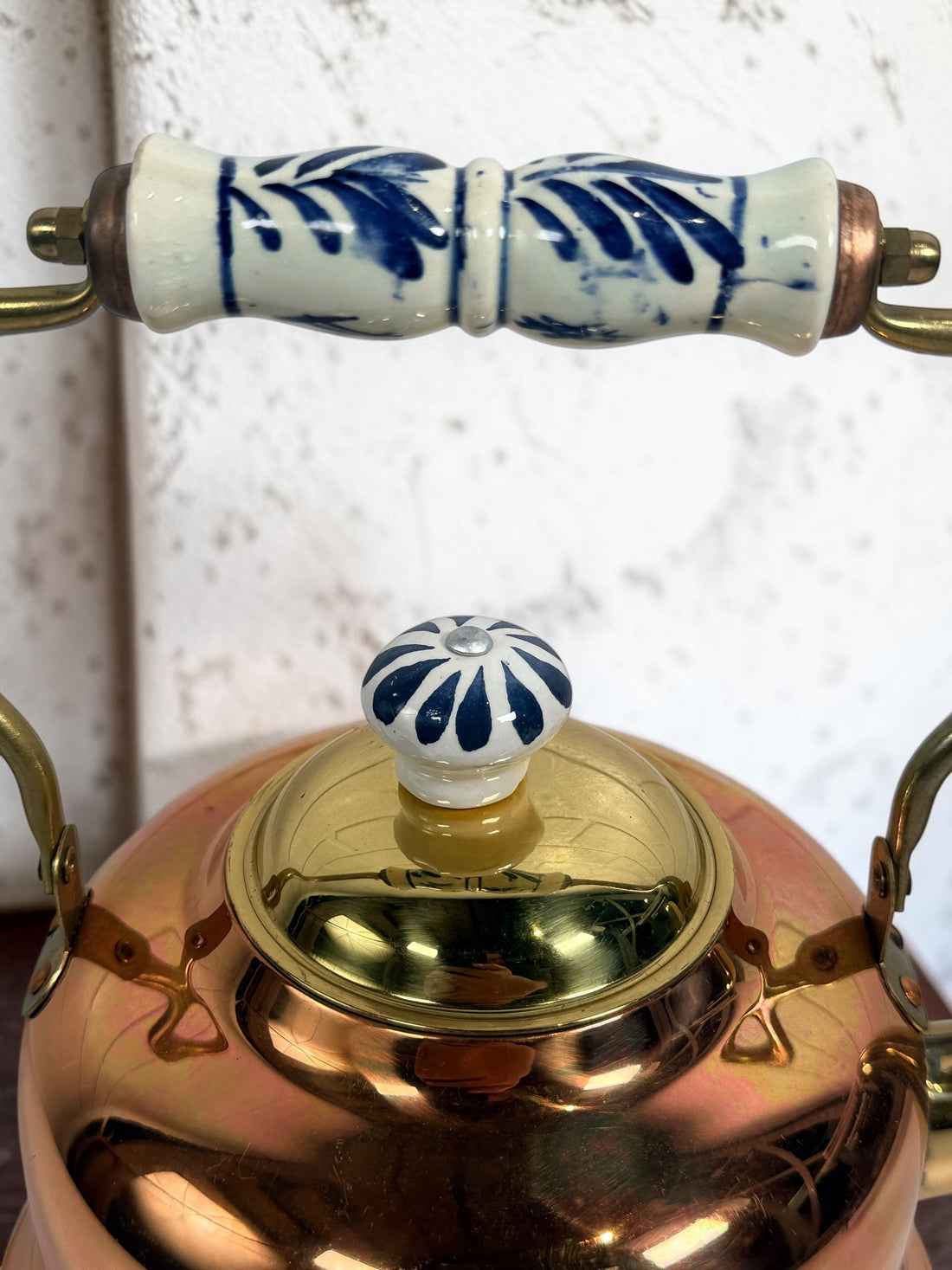 Vintage copper and brass tea kettle with blue-and-white porcelain handle and lid knob. Decorative Delft-style vintage kitchen collectible.