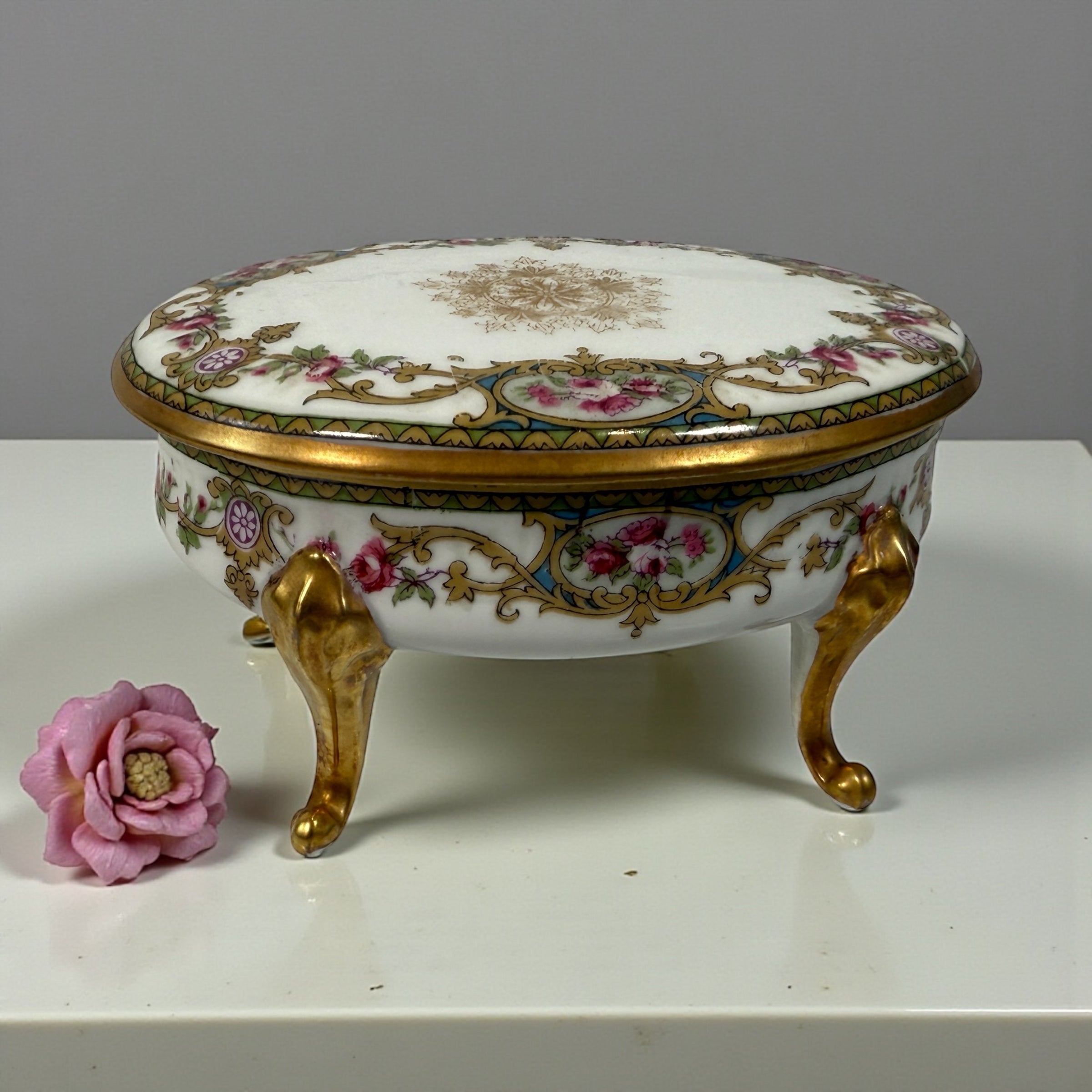 Antique French-style porcelain trinket box with gilt bronze legs, c.1900. Elegant vanity décor with floral details and classic Belle Époque charm.