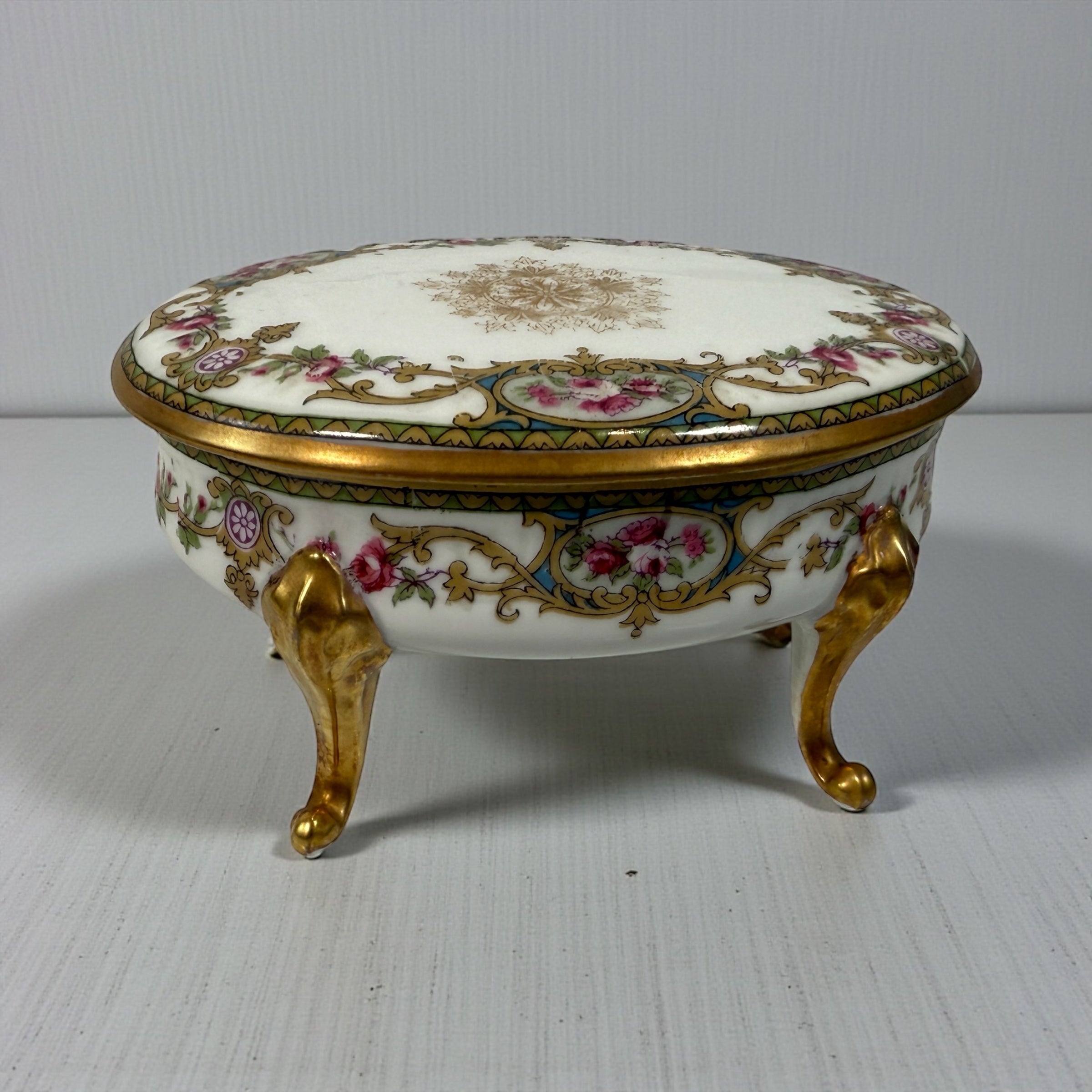 Antique French-style porcelain trinket box with gilt bronze legs, c.1900. Elegant vanity décor with floral details and classic Belle Époque charm.