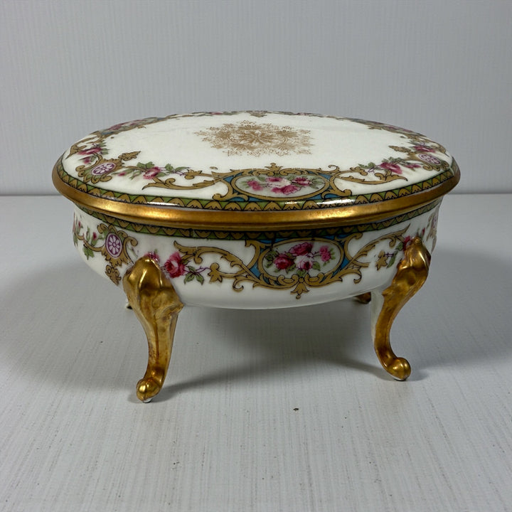 Antique French-style porcelain trinket box with gilt bronze legs, c.1900. Elegant vanity décor with floral details and classic Belle Époque charm.