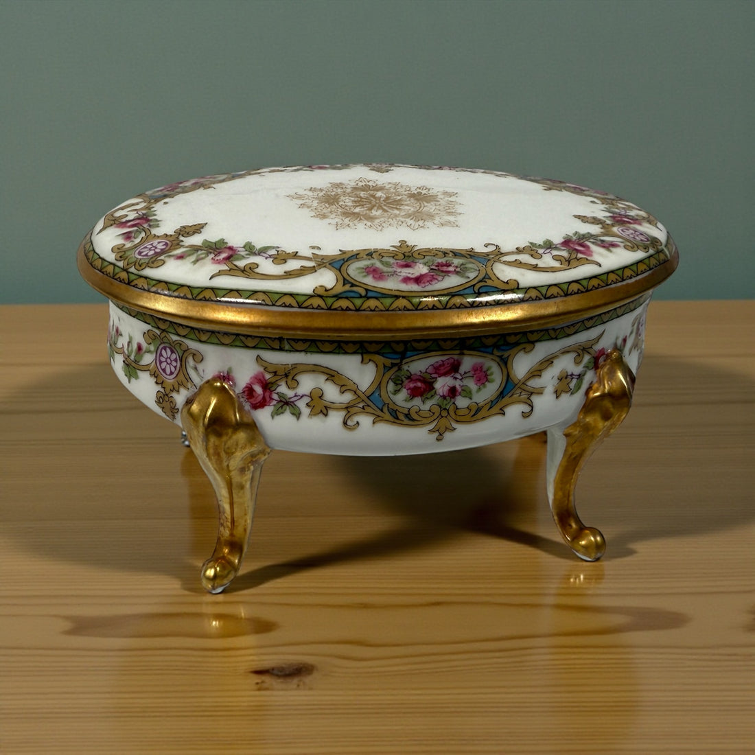 Antique French-style porcelain trinket box with gilt bronze legs, c.1900. Elegant vanity décor with floral details and classic Belle Époque charm.