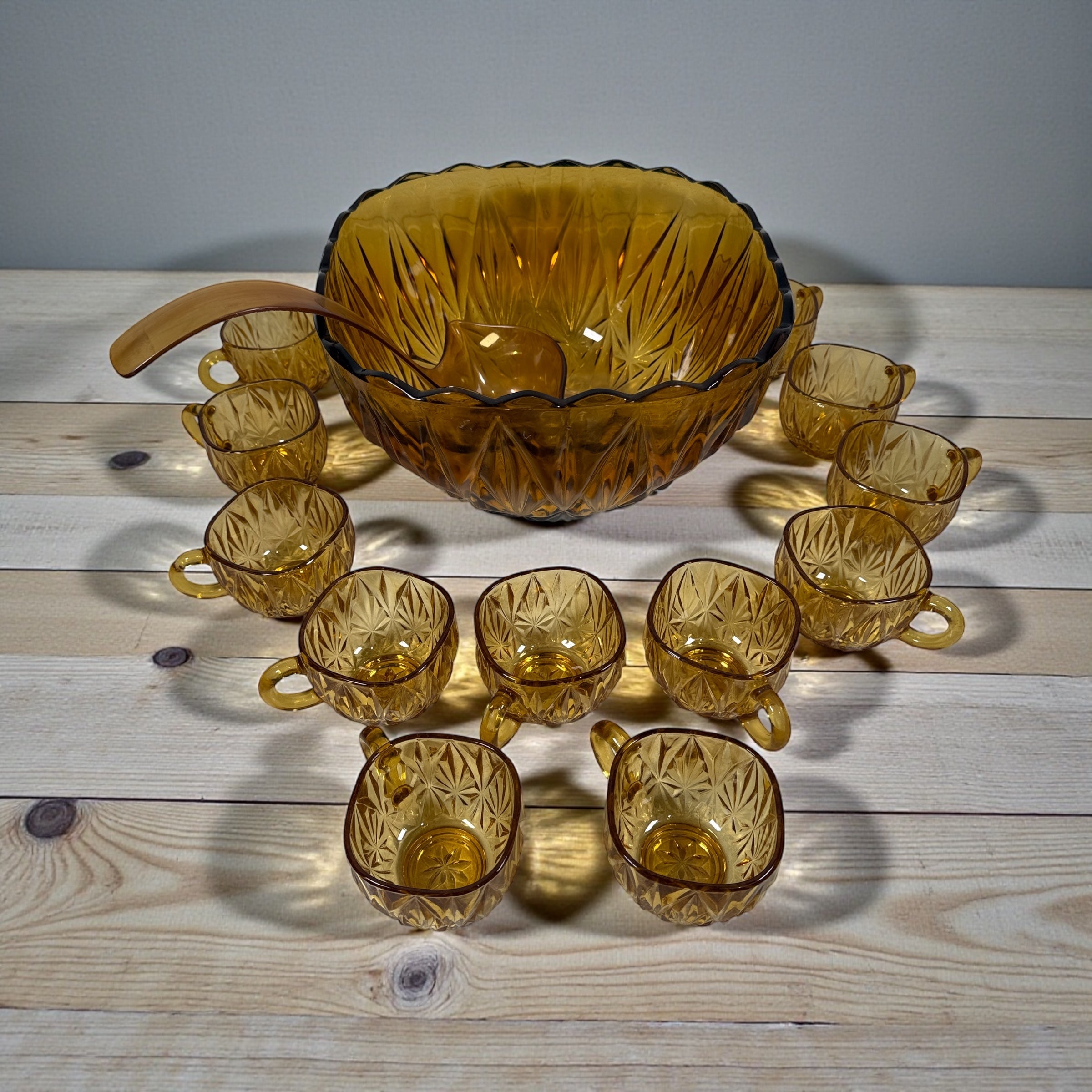 Vintage mid-century amber glass punch bowl set with cups and ladle. Classic starburst pattern, complete set, perfect for retro entertaining.