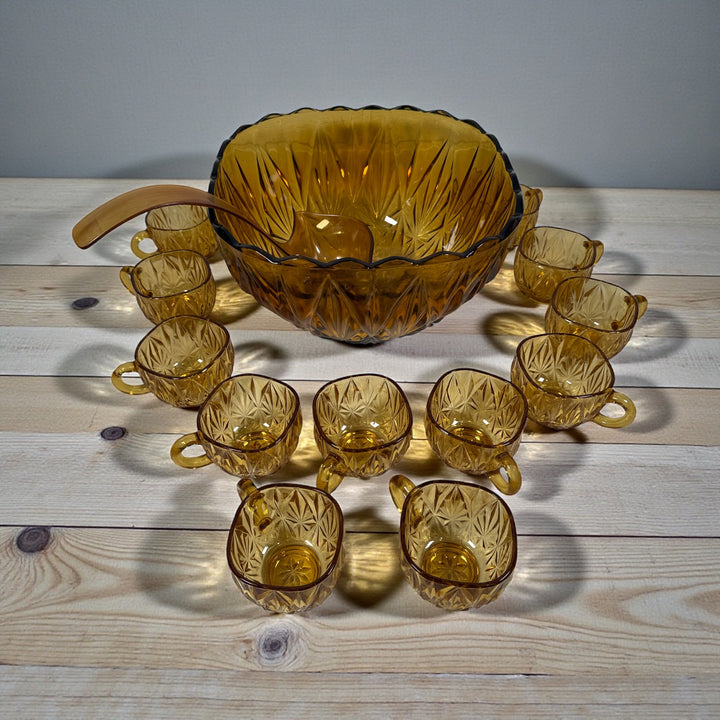 Vintage mid-century amber glass punch bowl set with cups and ladle. Classic starburst pattern, complete set, perfect for retro entertaining.