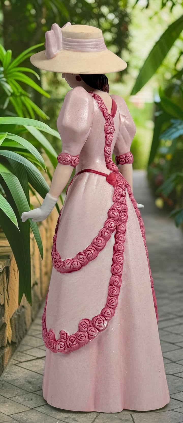 2015 Mrs. Albee Avon commemorative figurine featuring a Victorian lady in a pink rose-trimmed dress with marble-look column. Ceramic collectible award statue.