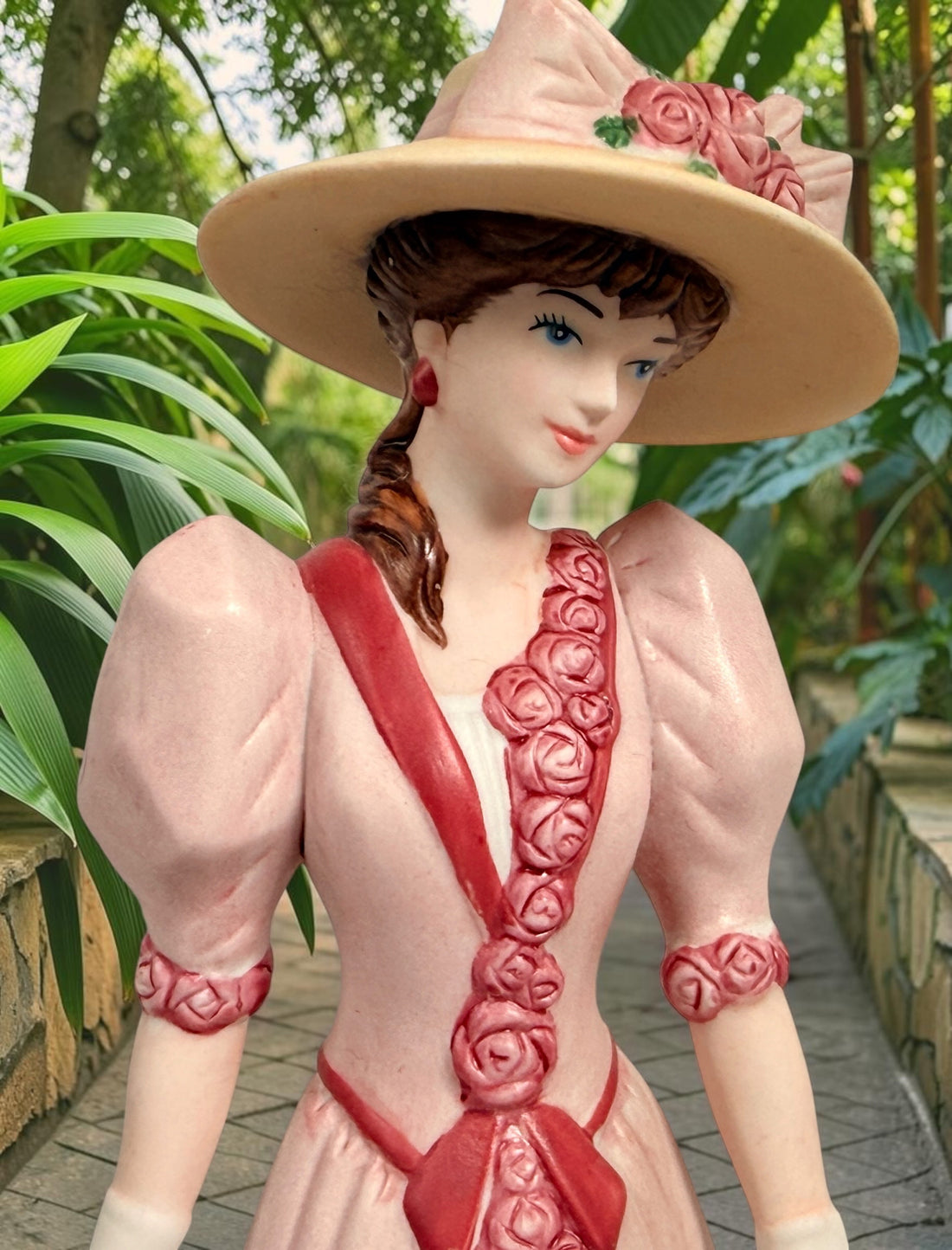 2015 Mrs. Albee Avon commemorative figurine featuring a Victorian lady in a pink rose-trimmed dress with marble-look column. Ceramic collectible award statue.