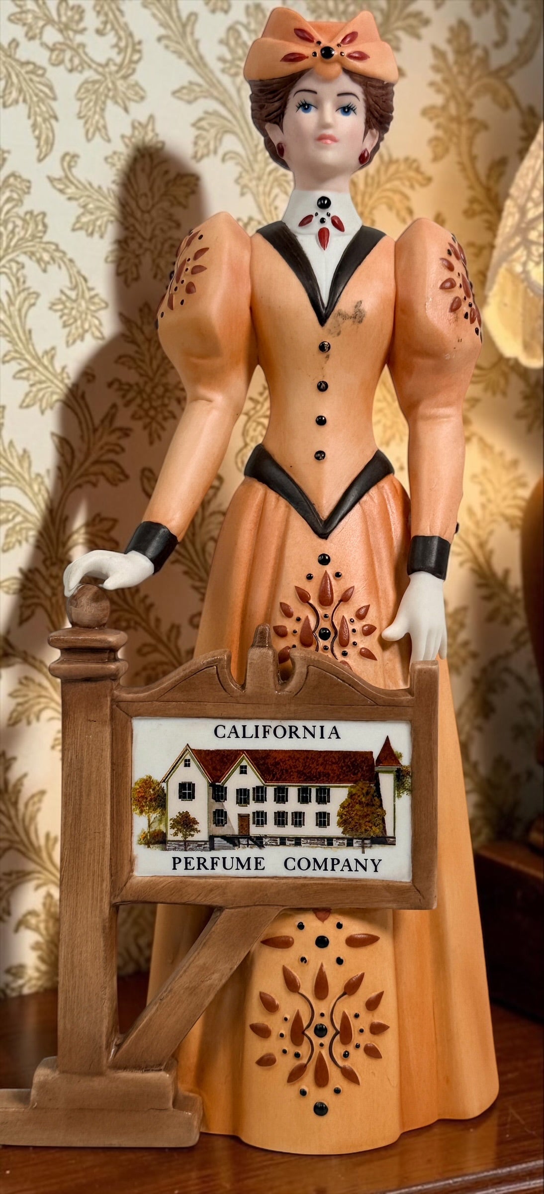 2013–2014 Avon Mrs. P.F.E. Albee award figurine featuring the California Perfume Company sign and Victorian dress. Ceramic collectible in good condition.
