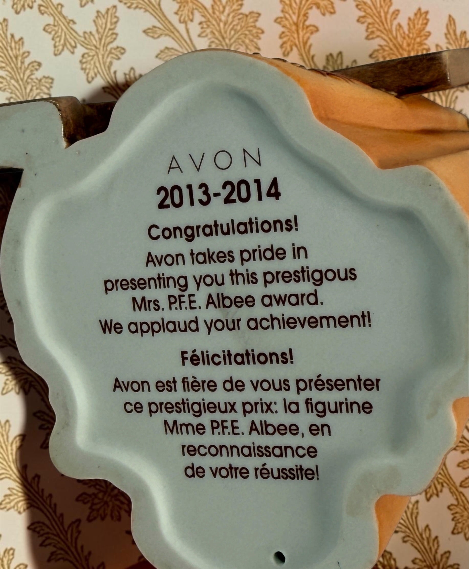 2013–2014 Avon Mrs. P.F.E. Albee award figurine featuring the California Perfume Company sign and Victorian dress. Ceramic collectible in good condition.
