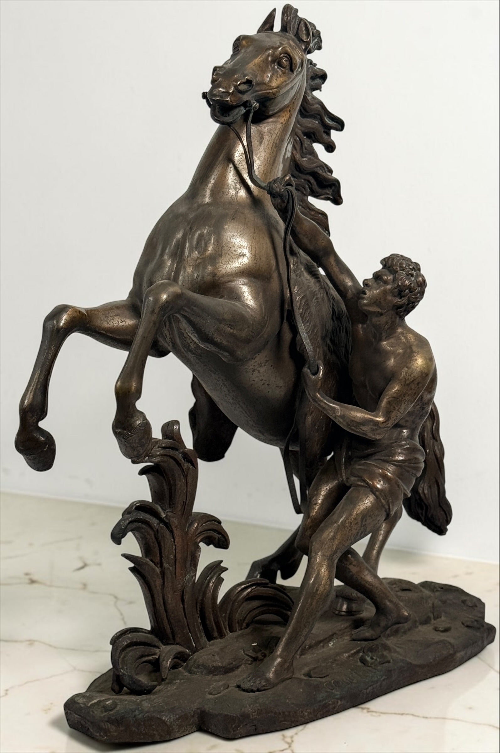 Antique Horse of Marly sculpture after Guillaume Coustou in patinated spelter, circa 1880–1910. Signed “Coustou,” featuring a dramatic horse tamer composition.