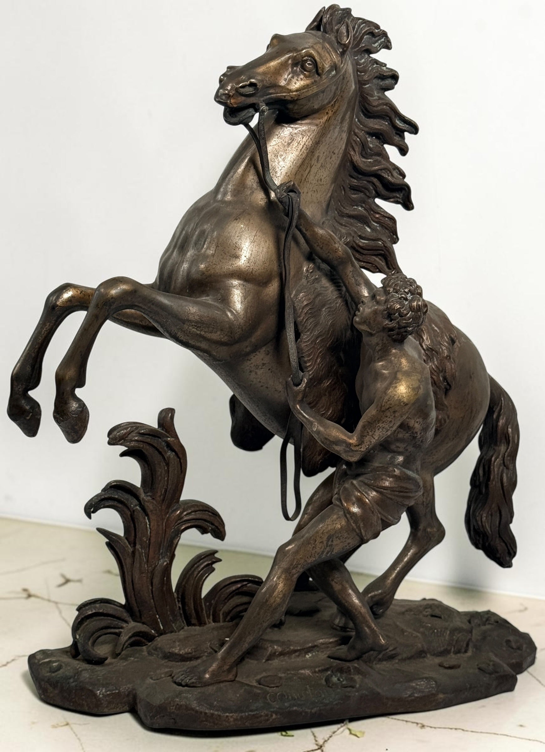 Antique Horse of Marly sculpture after Guillaume Coustou in patinated spelter, circa 1880–1910. Signed “Coustou,” featuring a dramatic horse tamer composition.