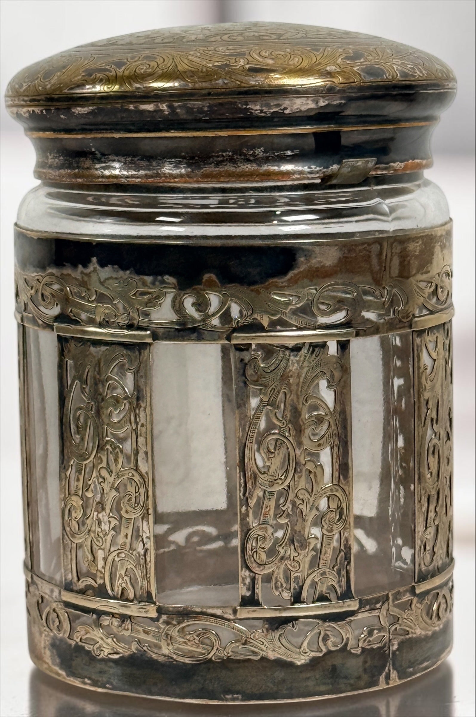 Antique Victorian glass tobacco humidor with ornate German silver overlay, engraved floral motifs, and domed lid. Elegant late-19th-century decorative storage jar.