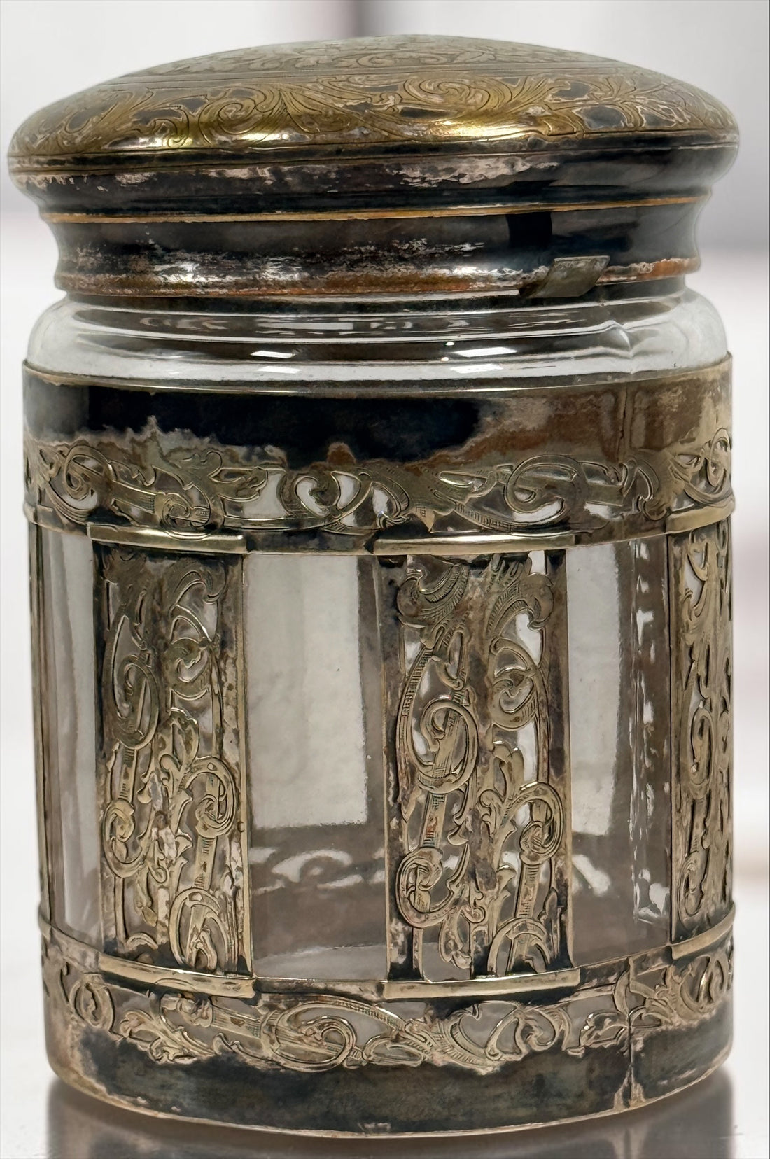 Antique Victorian glass tobacco humidor with ornate German silver overlay, engraved floral motifs, and domed lid. Elegant late-19th-century decorative storage jar.