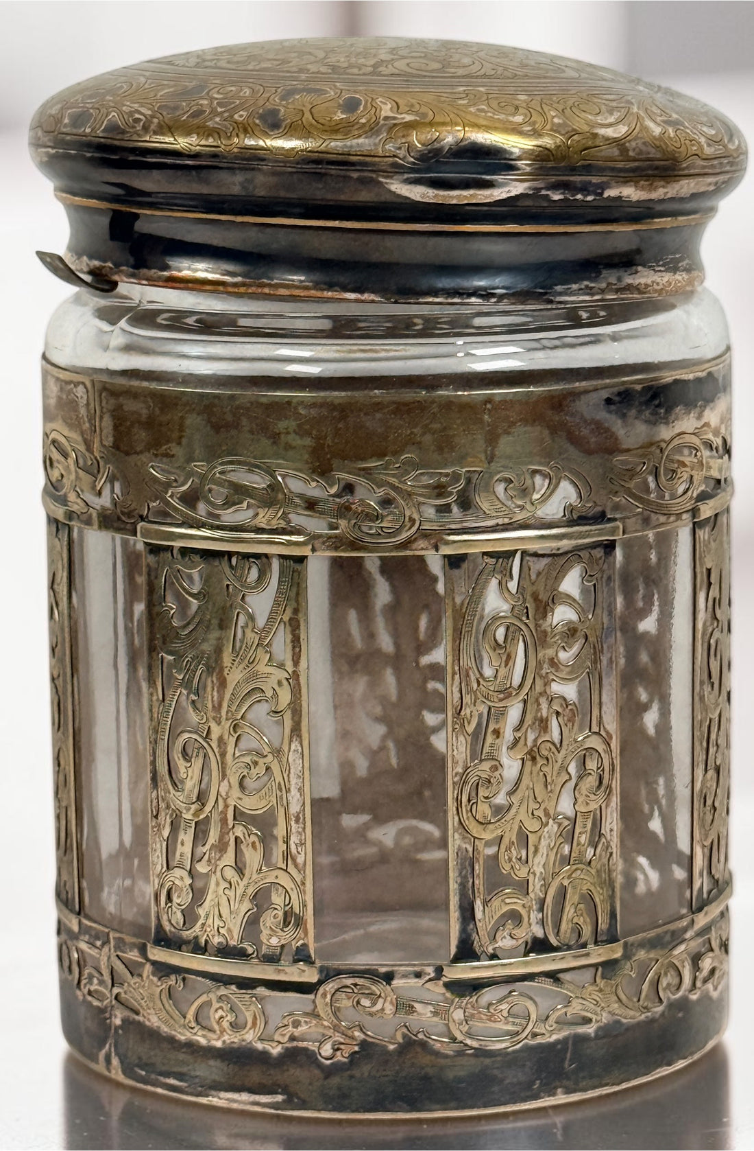 Antique Victorian glass tobacco humidor with ornate German silver overlay, engraved floral motifs, and domed lid. Elegant late-19th-century decorative storage jar.