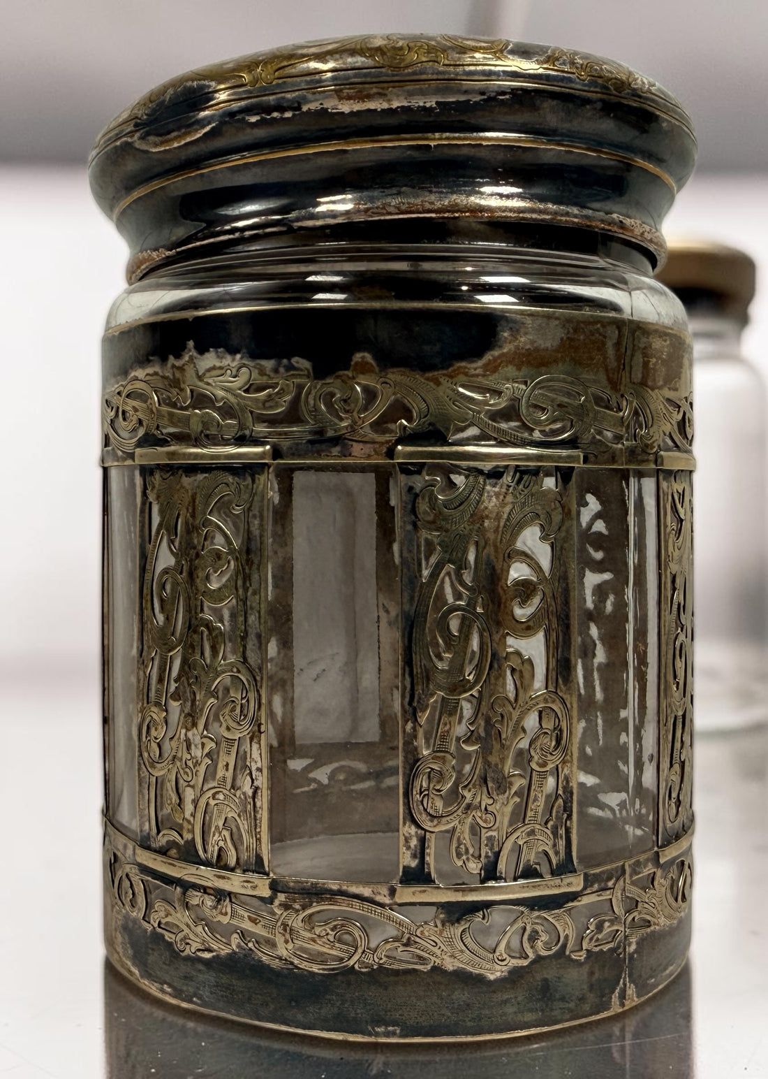 Antique Victorian glass tobacco humidor with ornate German silver overlay, engraved floral motifs, and domed lid. Elegant late-19th-century decorative storage jar.